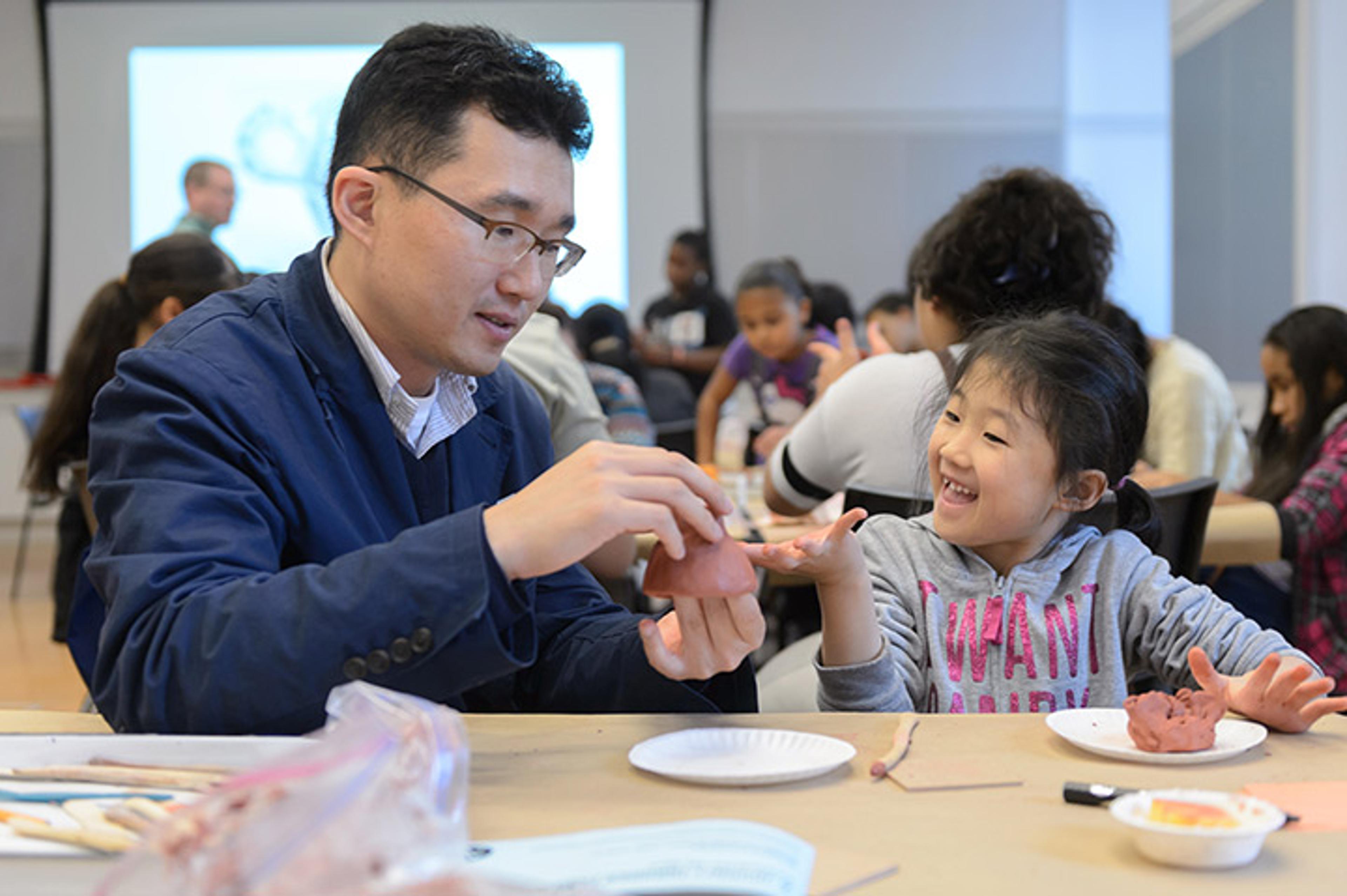 A father and daughter sculpt with clay