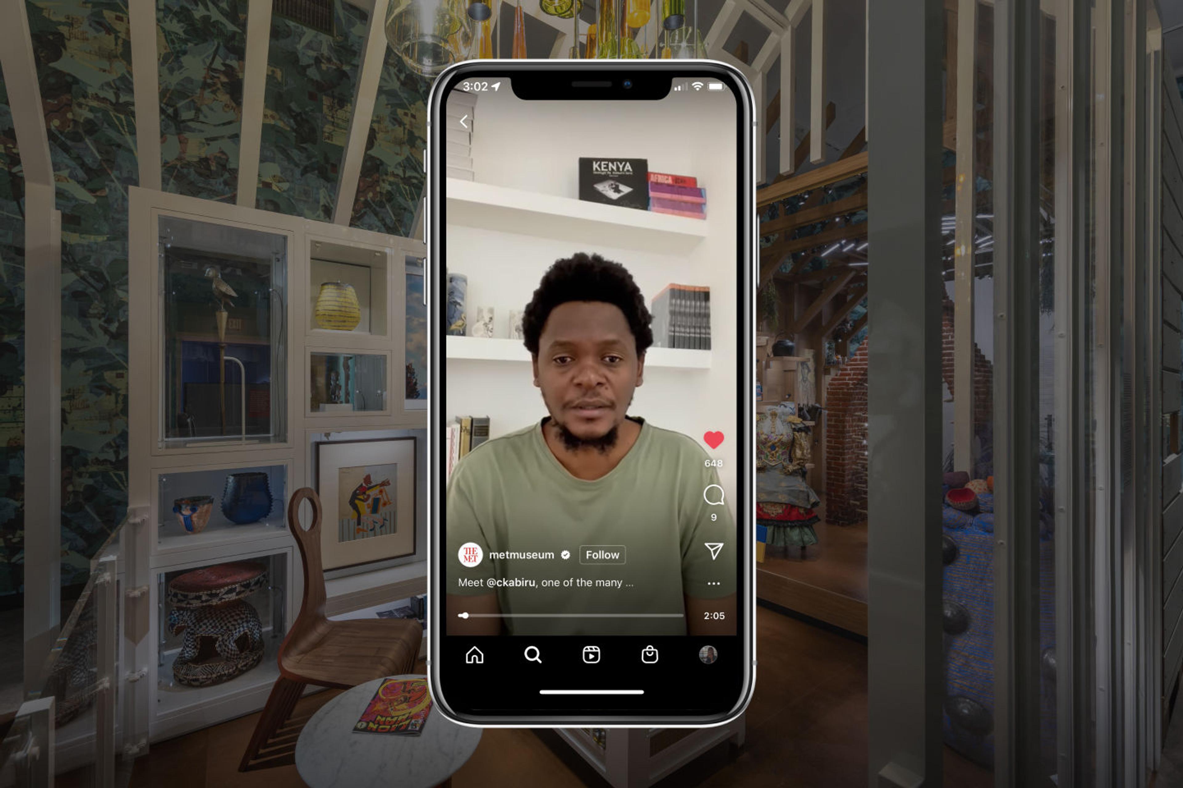The artist Cyrus Kabiru appears on a phone against a backdrop of the Afrofuturist period room exhibition.