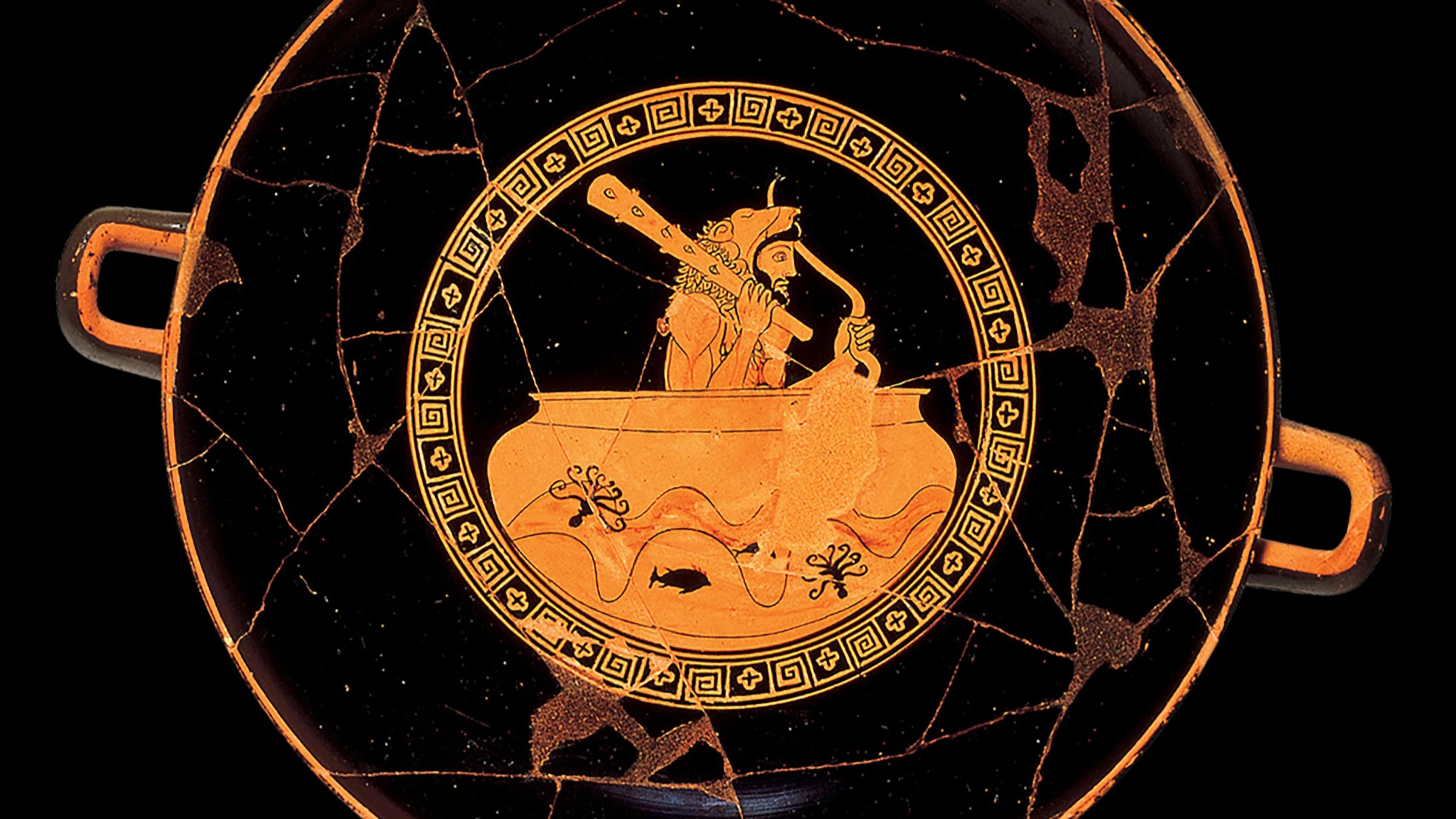Interior of a red-figure kylix (drinking cup) showing a bearded man wearing a lion-skin headdress and cloak, seated in a large cauldron floating on wavy water, holding a knotted club across his shoulders. Small fish and coral or seaweed shapes appear in the water below.