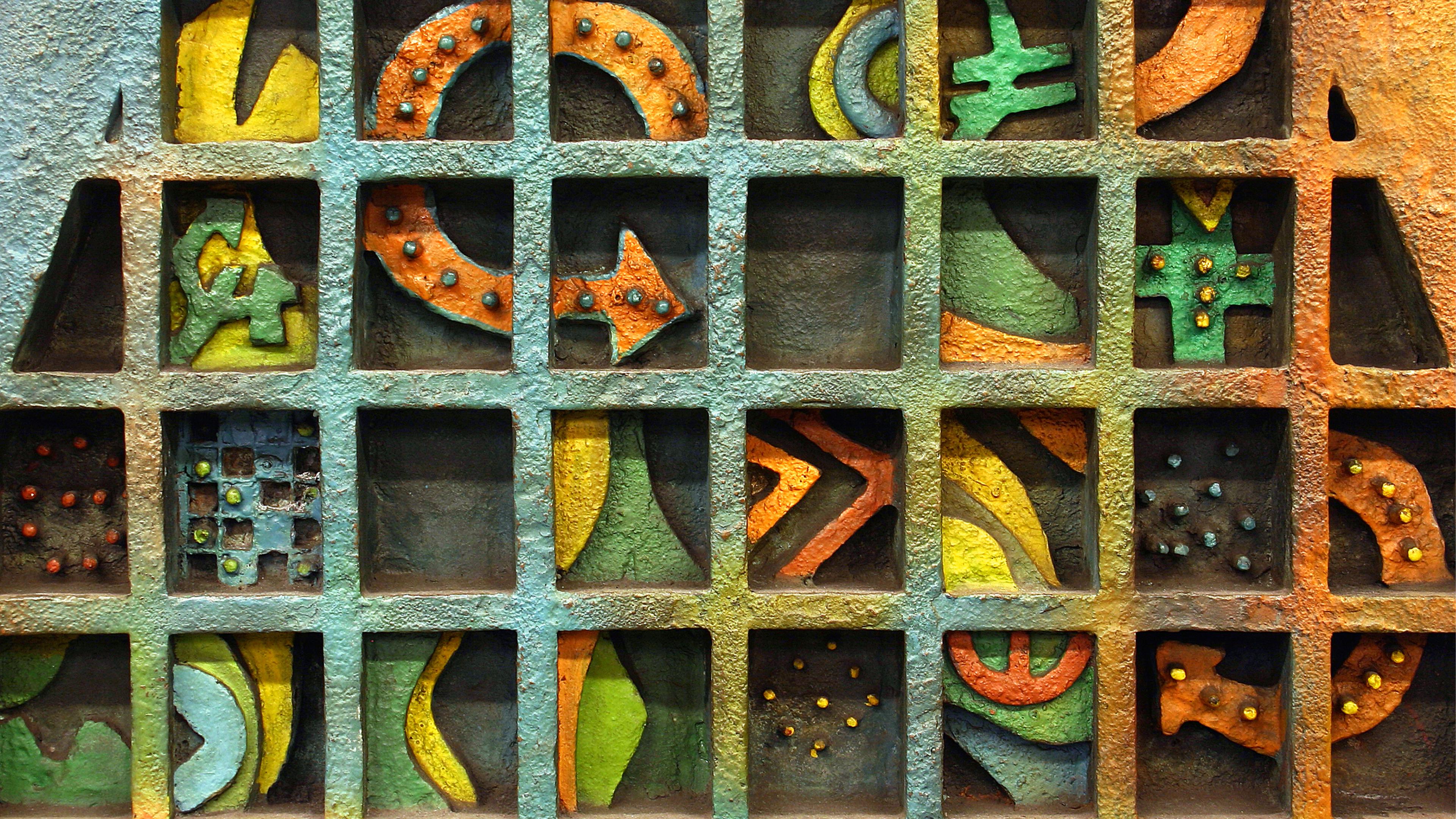 Detail image of metal square with multi figured object with a variety of colors like orange, yellow and green. 