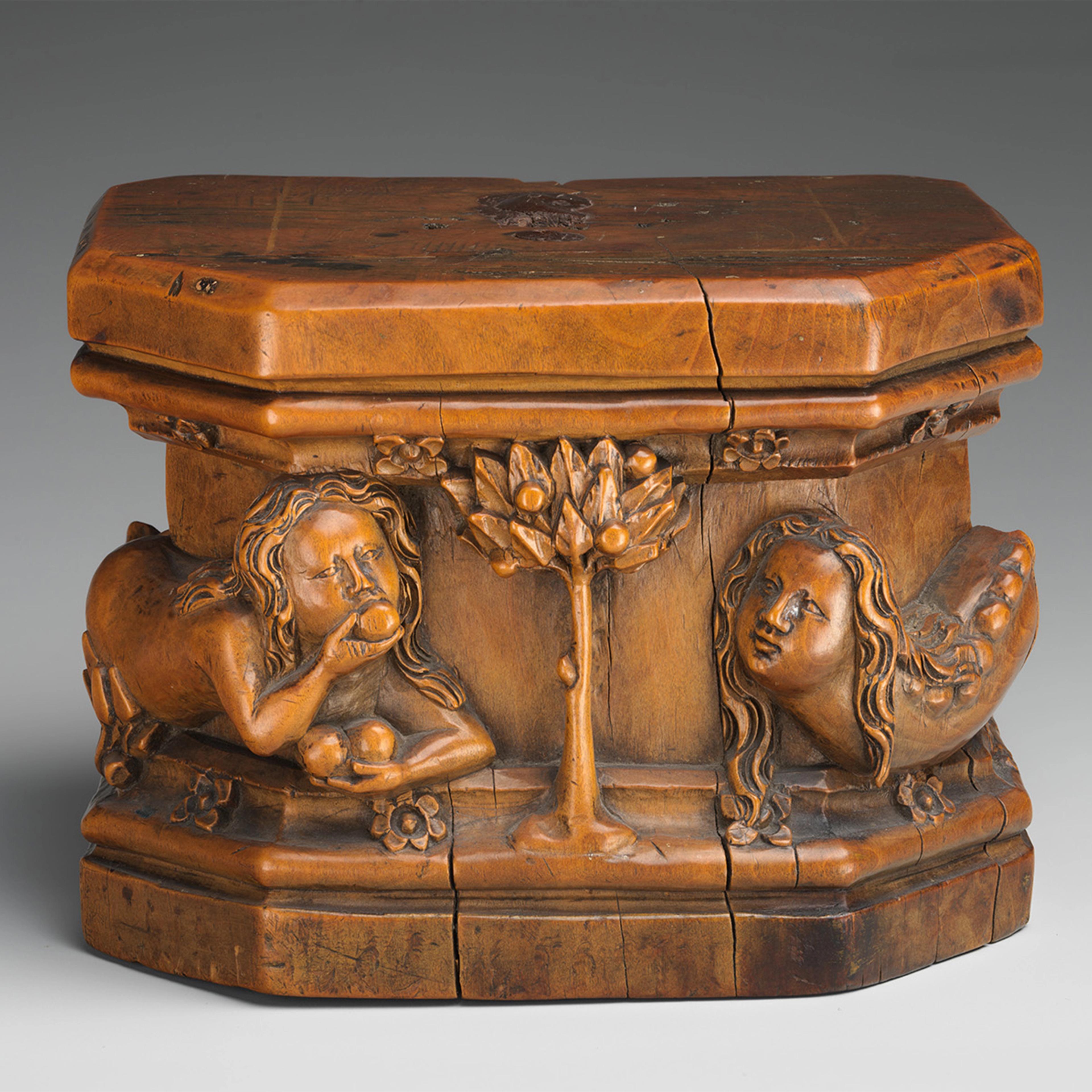 A small wooden carved box featuring figures and a tree in relief.