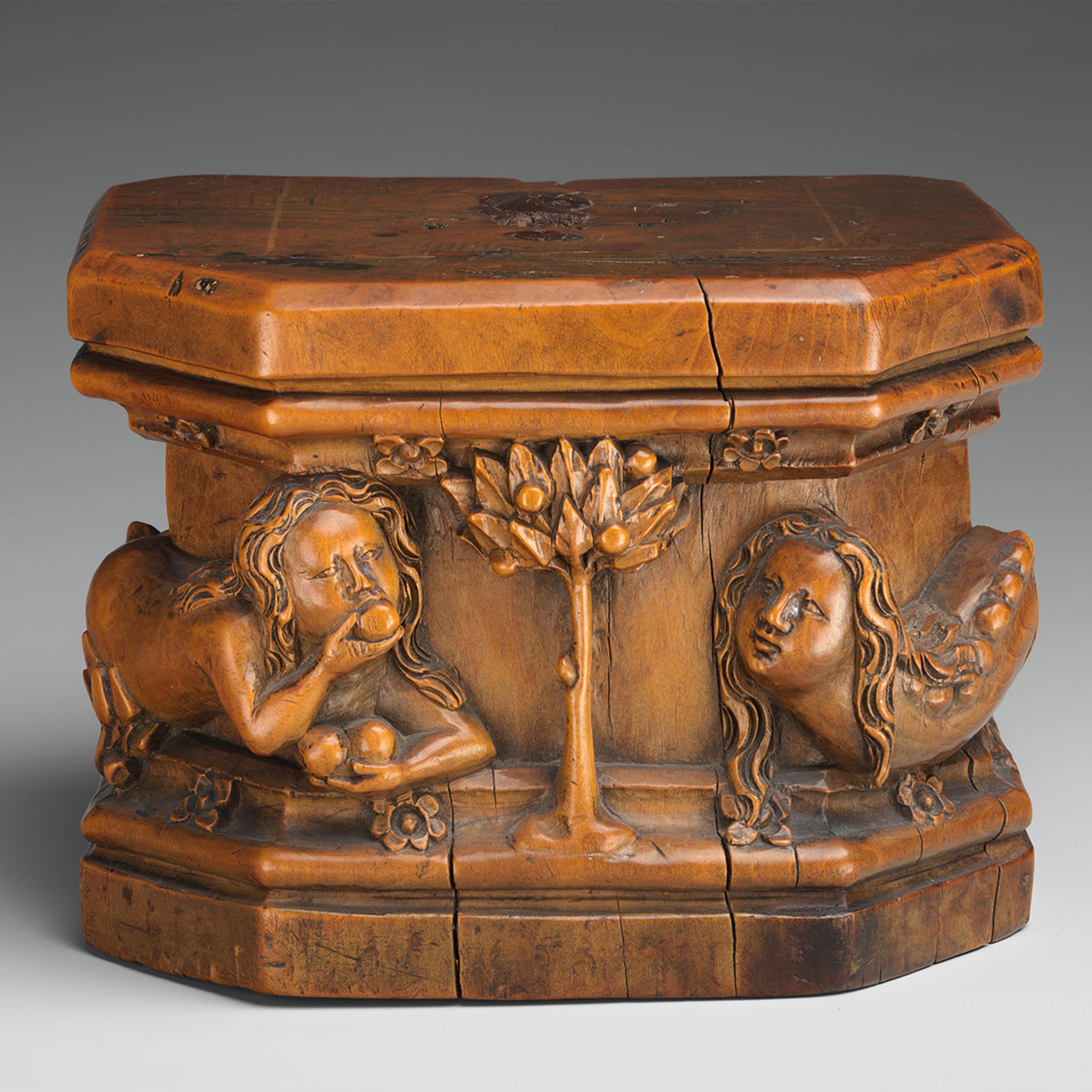 A small wooden carved box featuring figures and a tree in relief.