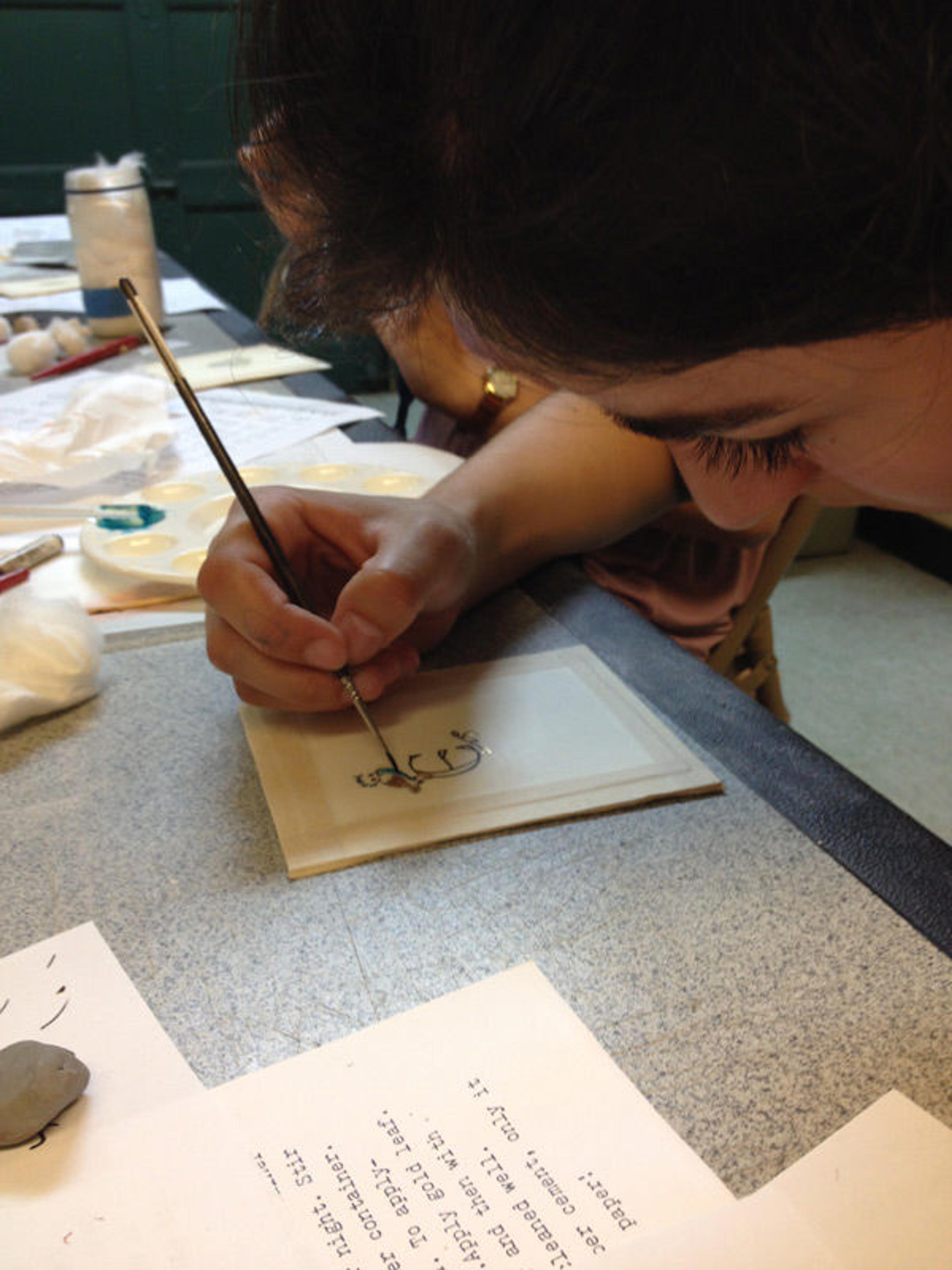 Cloisters intern Emma Perloff painting an illuminated initial