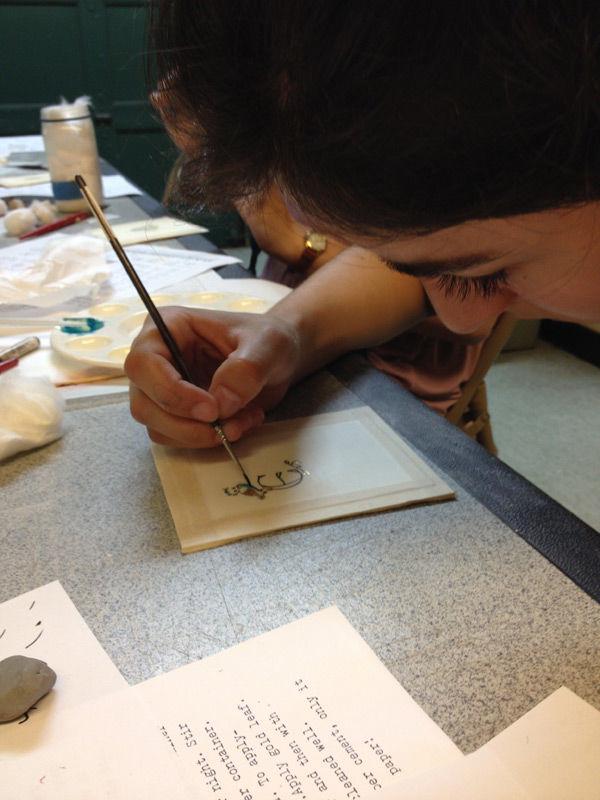 Cloisters intern Emma Perloff painting an illuminated initial