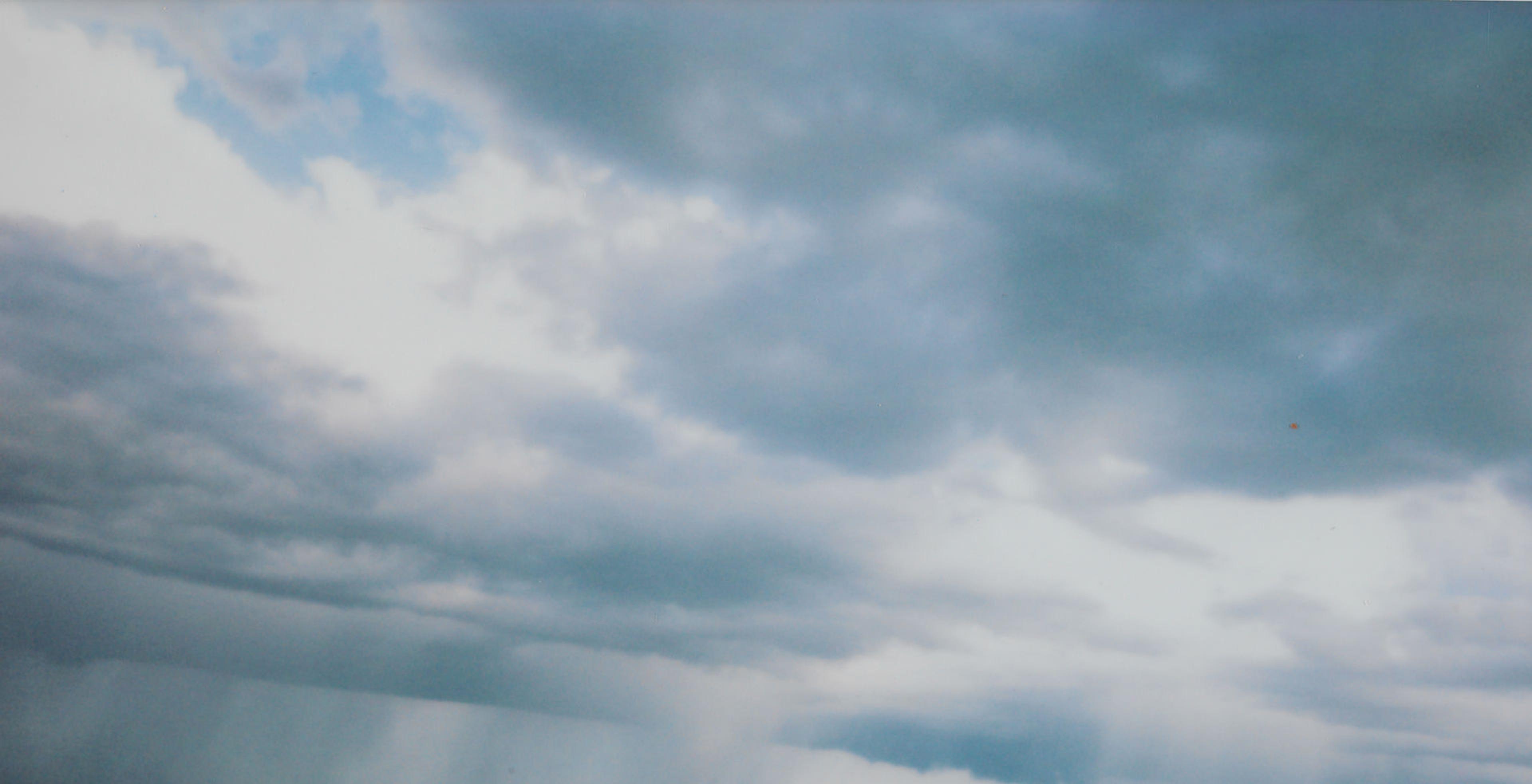 Sky with puffy blue and white clouds. A light blue sky peeks through the top right corner of the image.