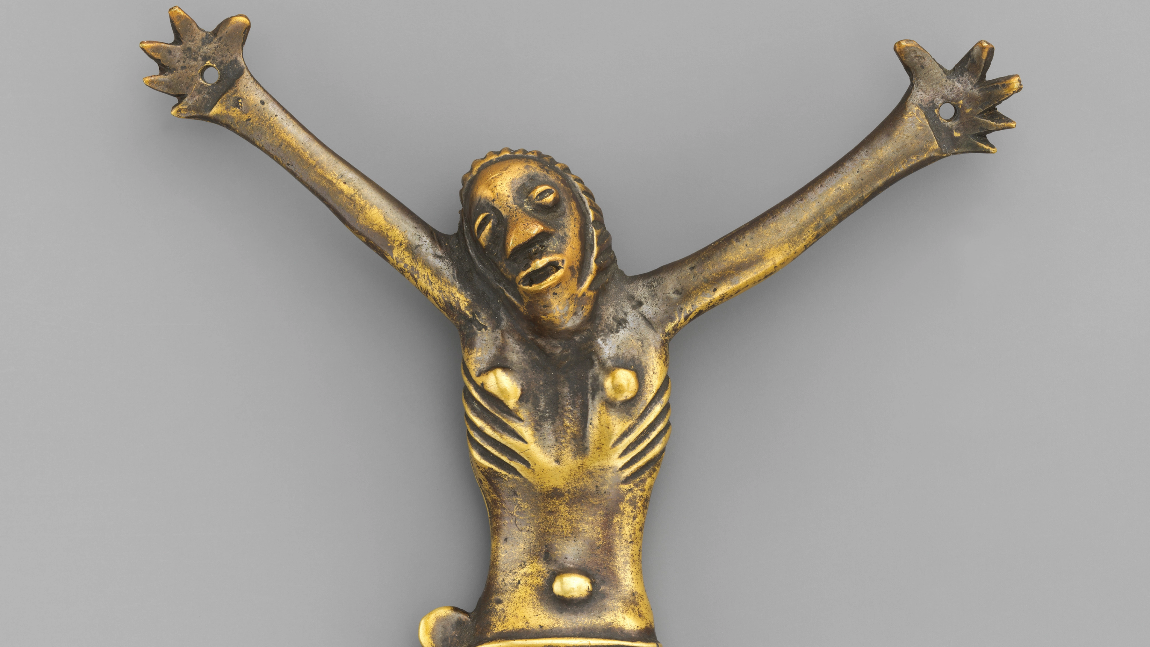Brass figure of Christ with arms extended.