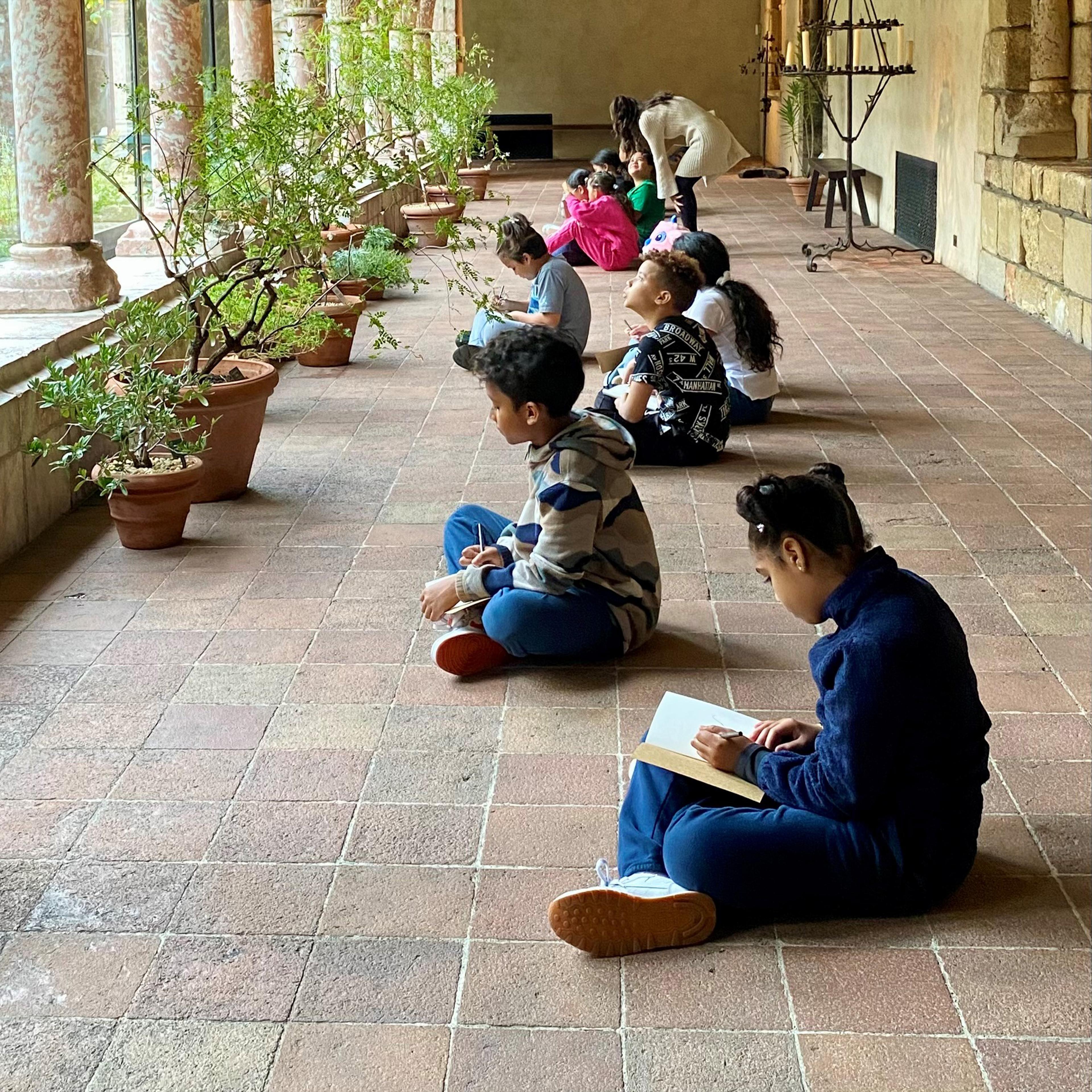 School children sitting cross legged with books in their laps reading.