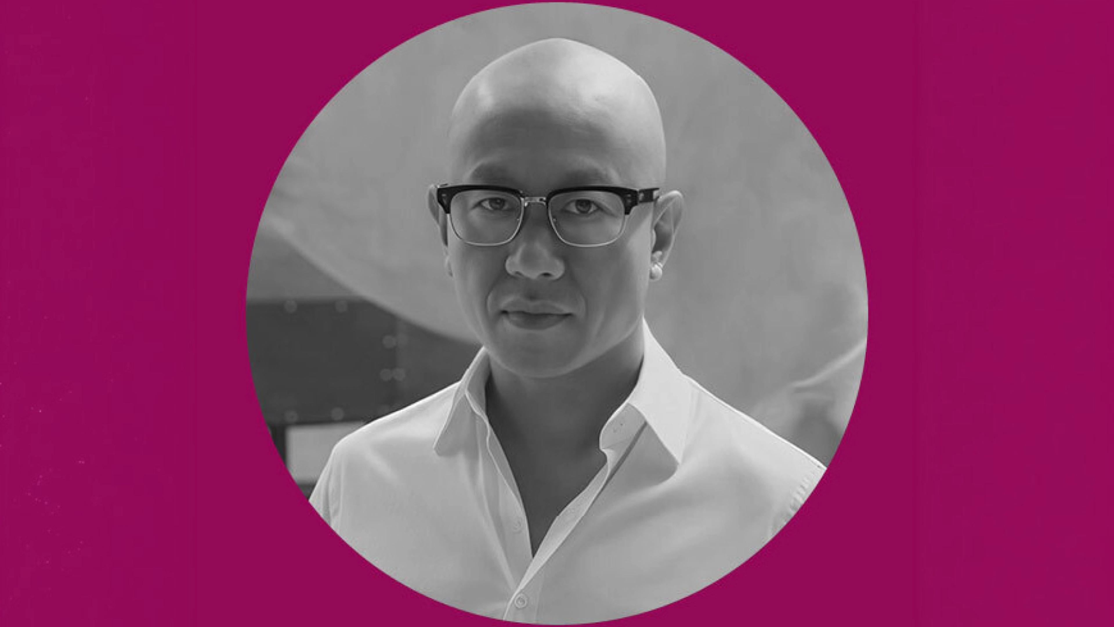 Black-and-white portrait of a man in a white collared shirt and glasses, framed in a circle and surrounded by a magenta background.