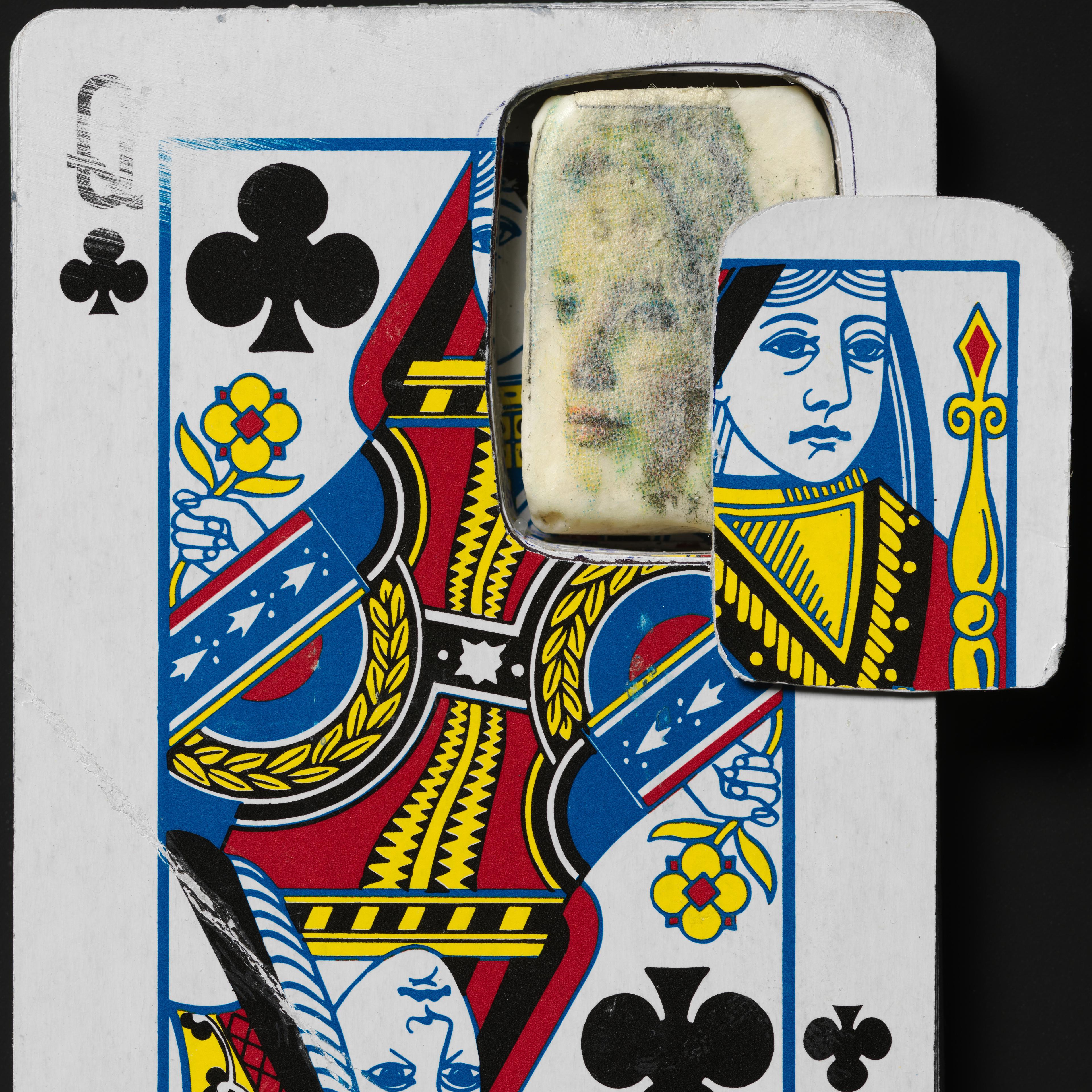 Close-up of a Queen of Clubs playing card with a cut-out section. Behind it, a faded, ghostly face is visible, creating a surreal, mysterious mood.