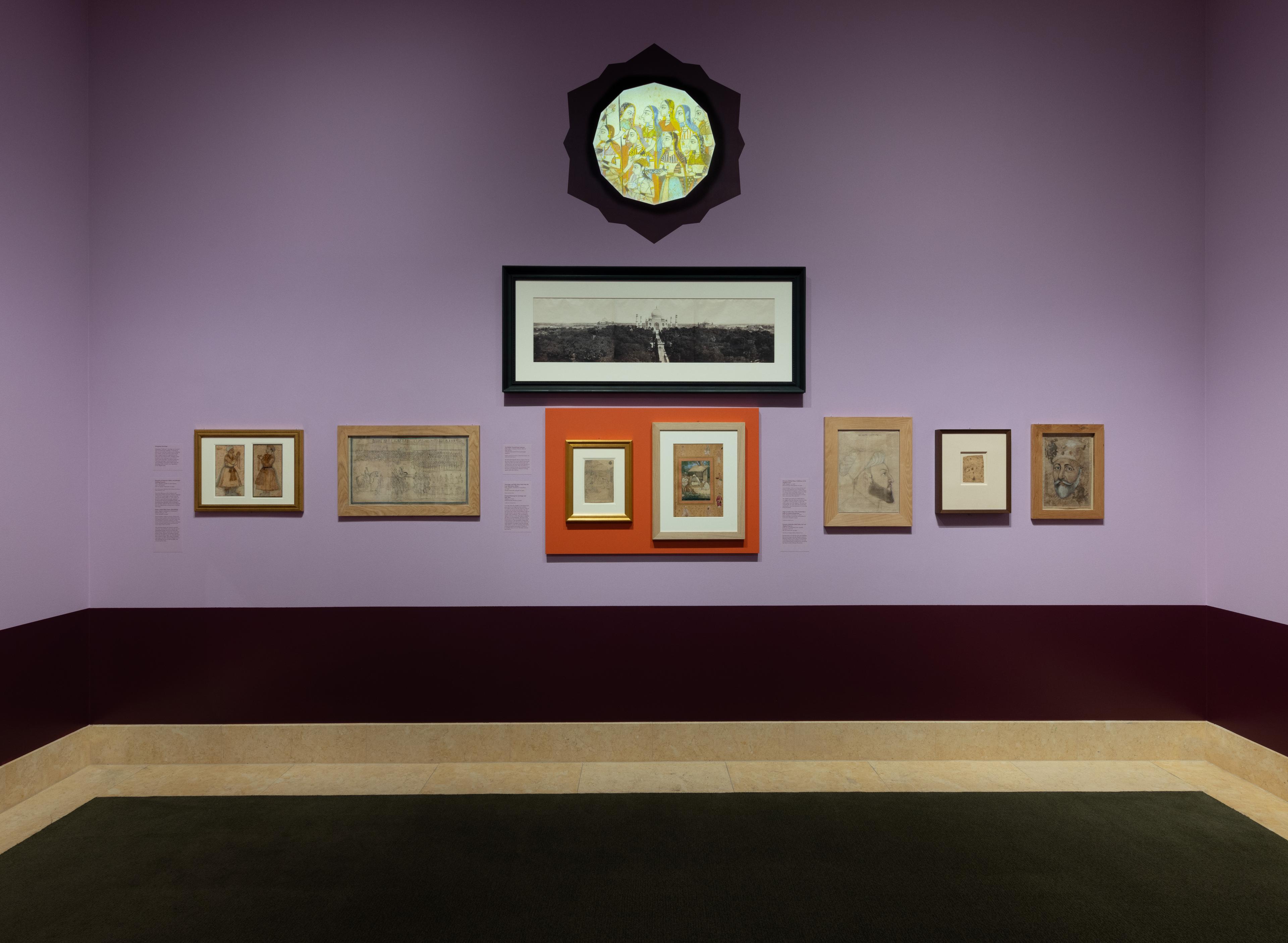 An art gallery room with purple walls displays framed historical paintings. The pieces are varied in size, and a glass display case is partially visible.