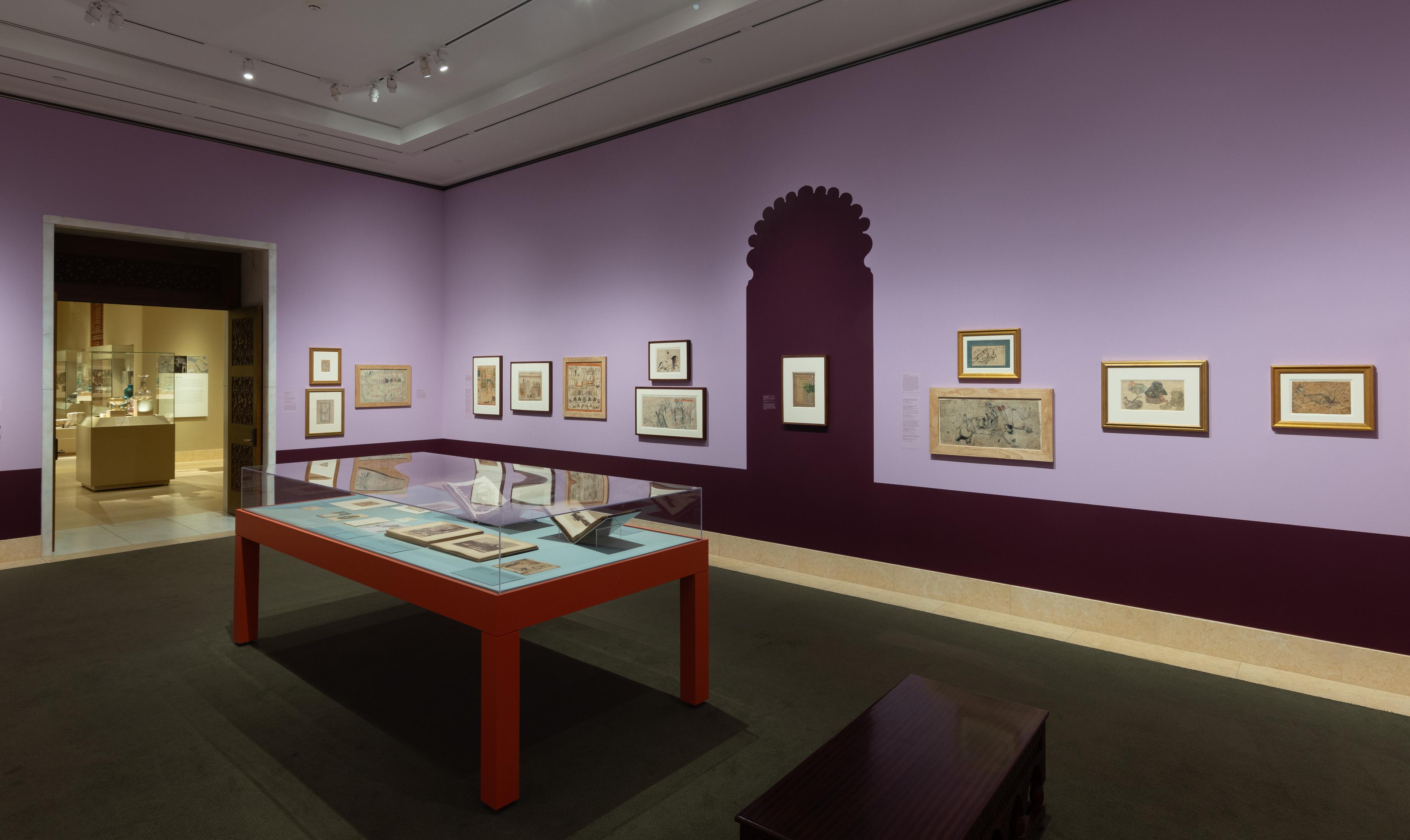 An art gallery room with purple walls displays framed historical paintings. The pieces are varied in size, and a glass display case is partially visible.