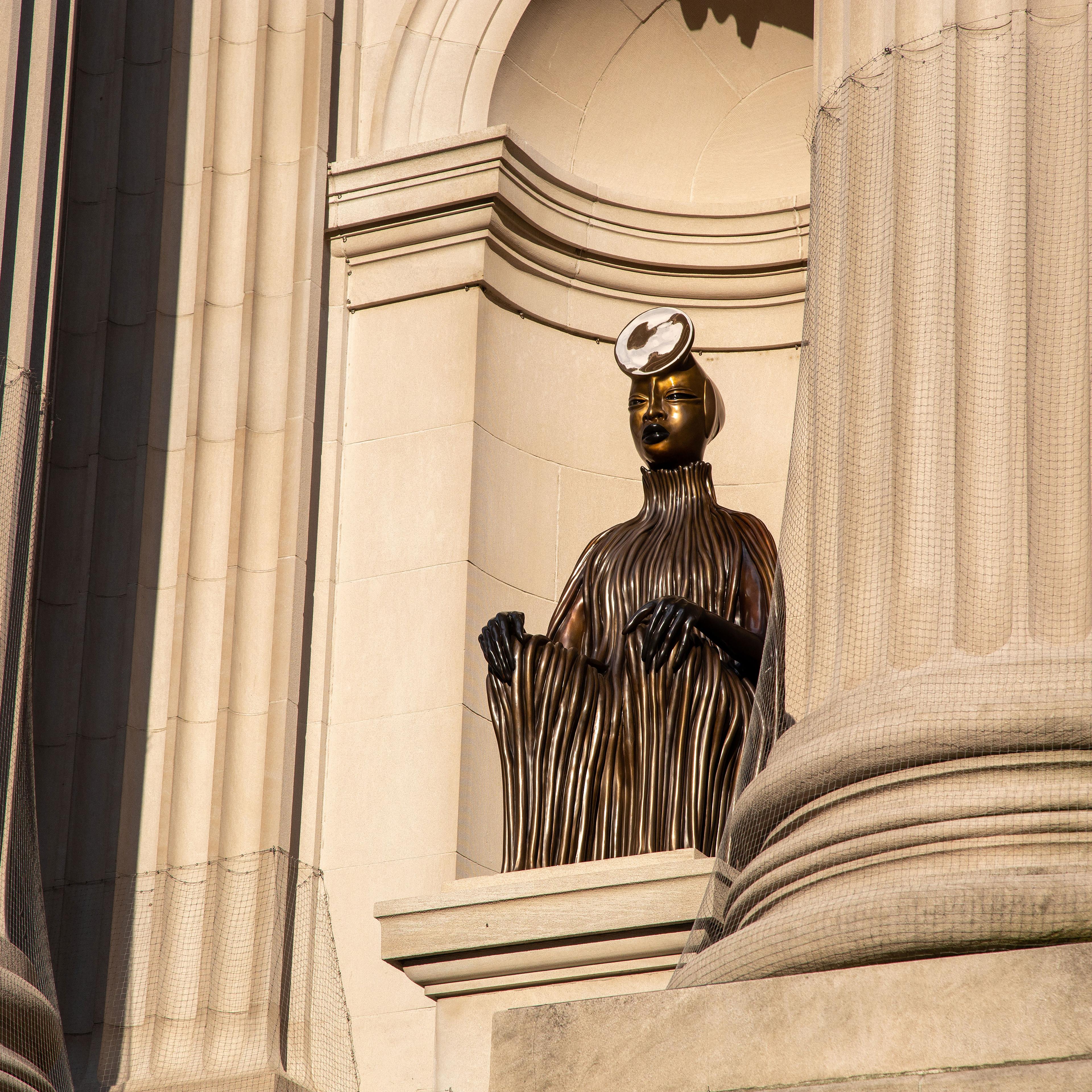 A bronze figure sits in a niche in the facade of The Metropolitan Museum of Art