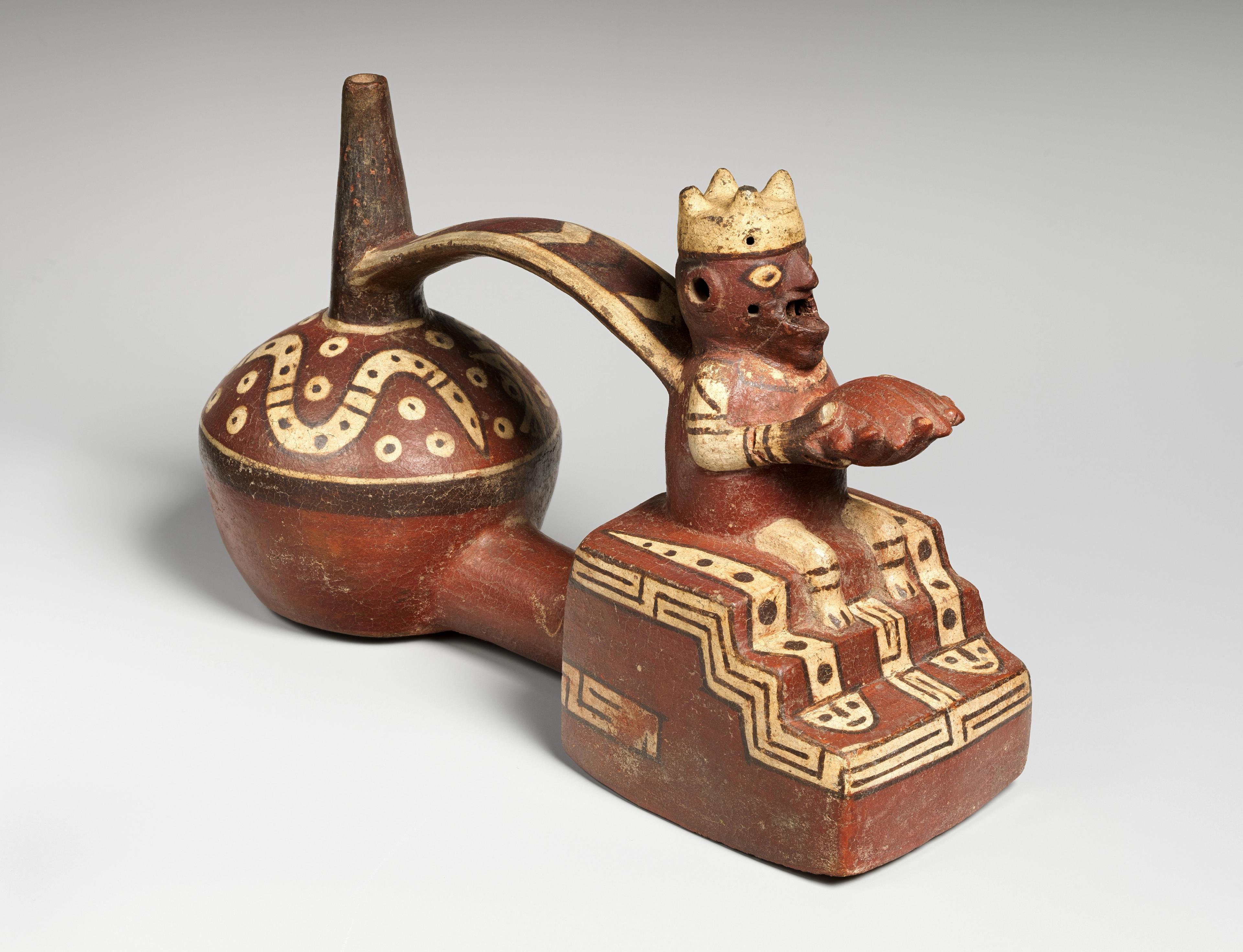 Double-chambered ceramic Wari vessel. One chamber is shaped like a typical bottle with painted details, while the other chamber is shaped as a seated figure holding a shell.
