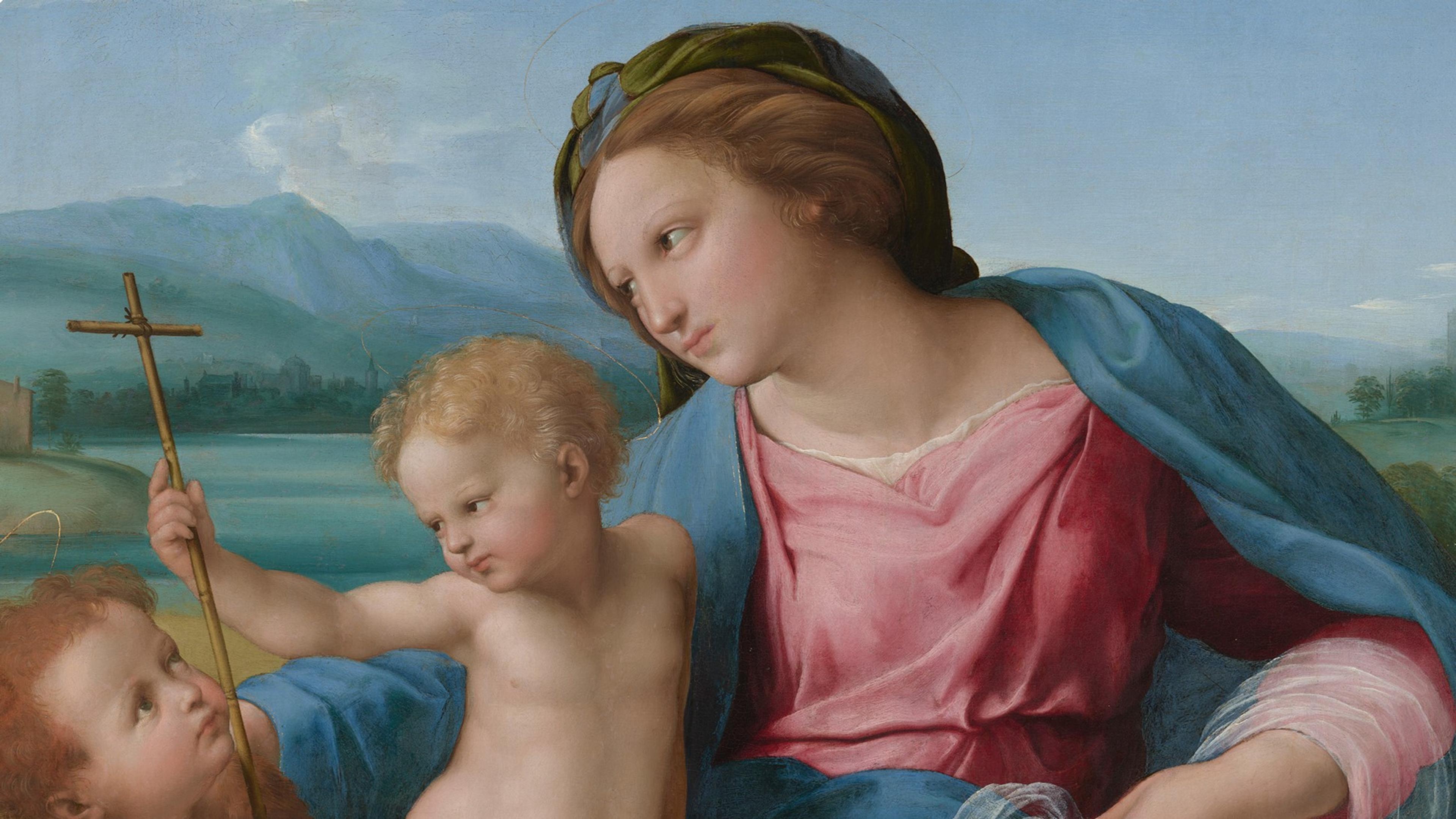A woman in a fabric cloak holds on to a baby holding a cross while another small child looks on
