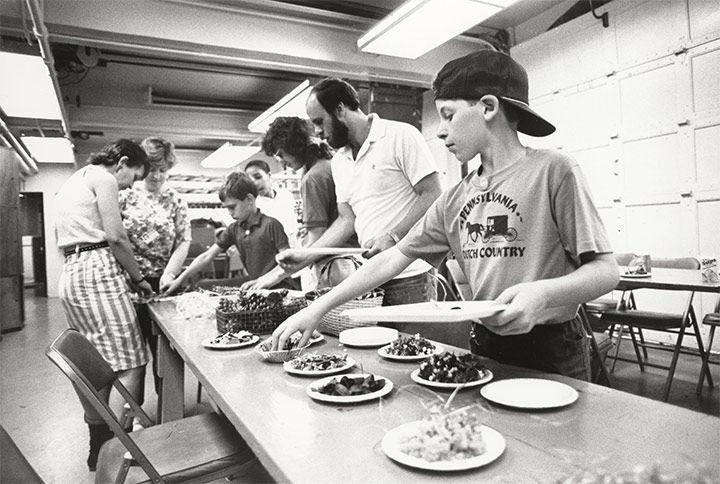 Archival photo of adults and children gathering materials during museum class.