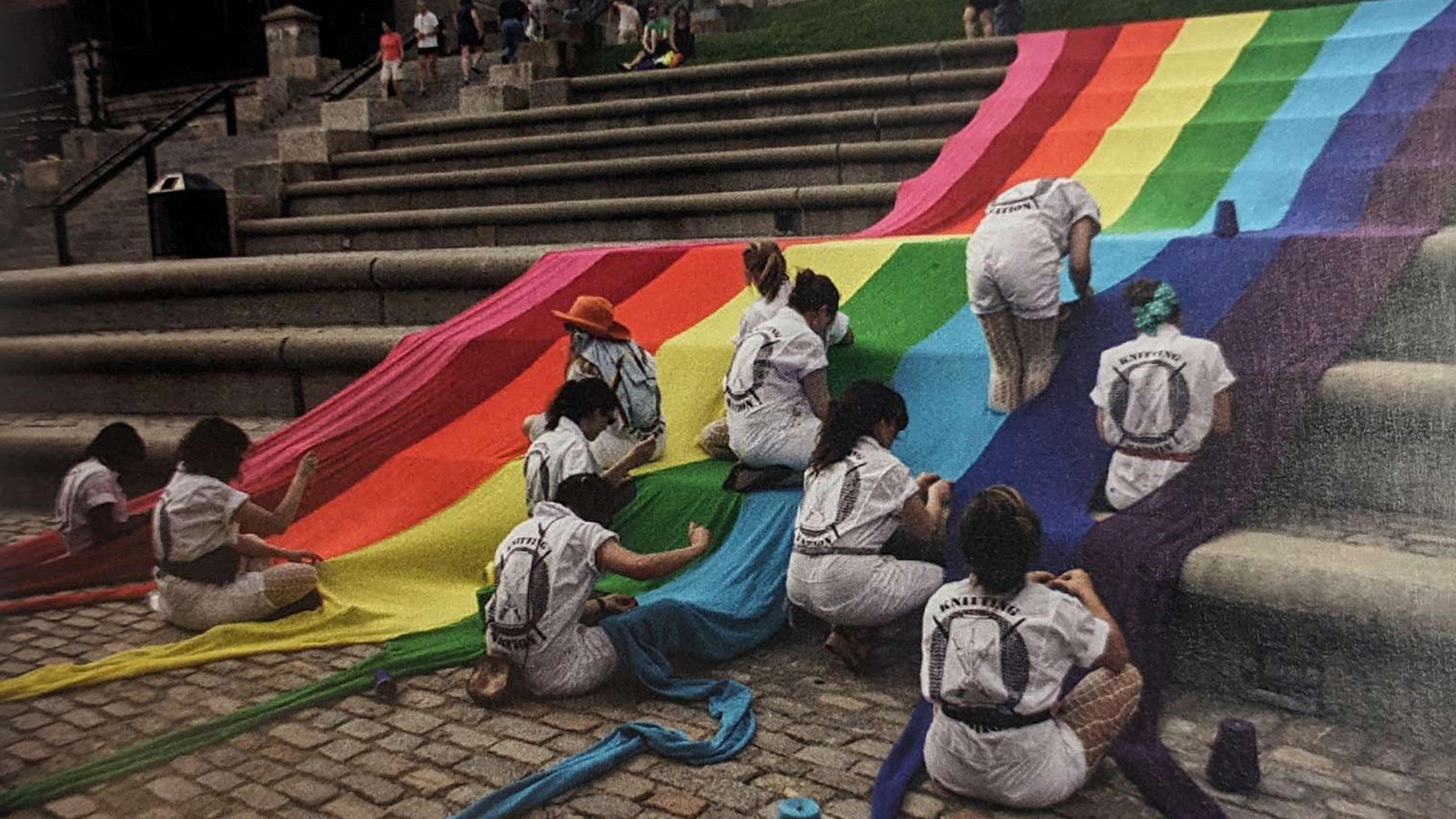 Pride flag being draped over a large public staircase