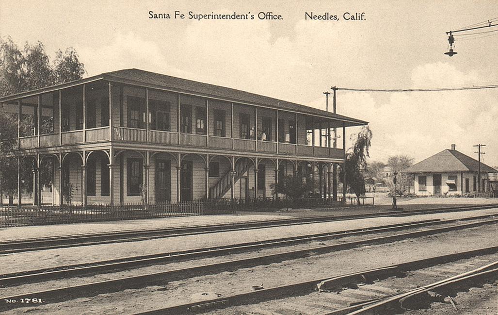 Black and white postcard of a train station with text that reads, "Santa Fe Superintendent's Office. Needles, Calif."