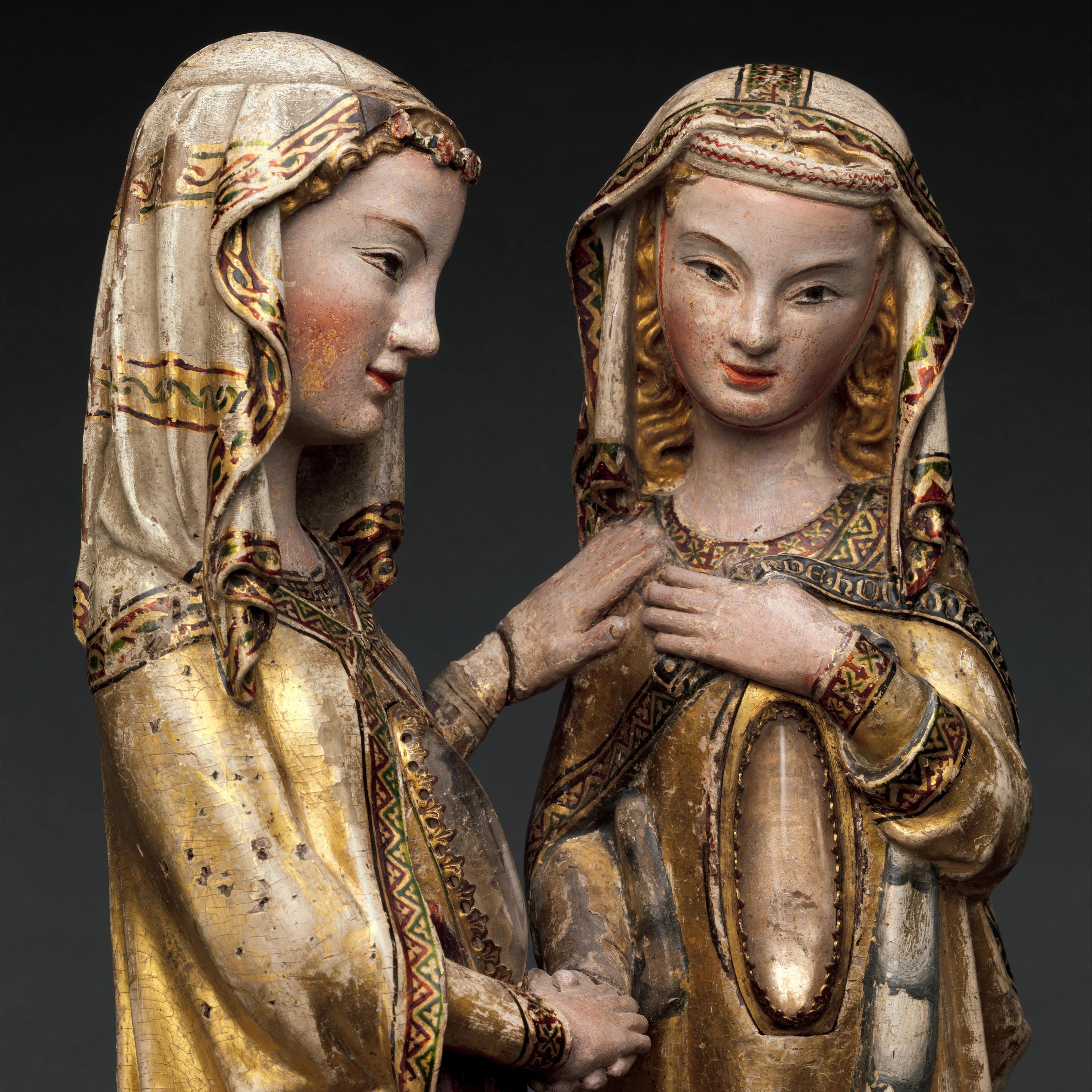 Two medieval sculptures of women with serene expressions, wearing ornate headdresses and robes with intricate patterns, set against a dark background.