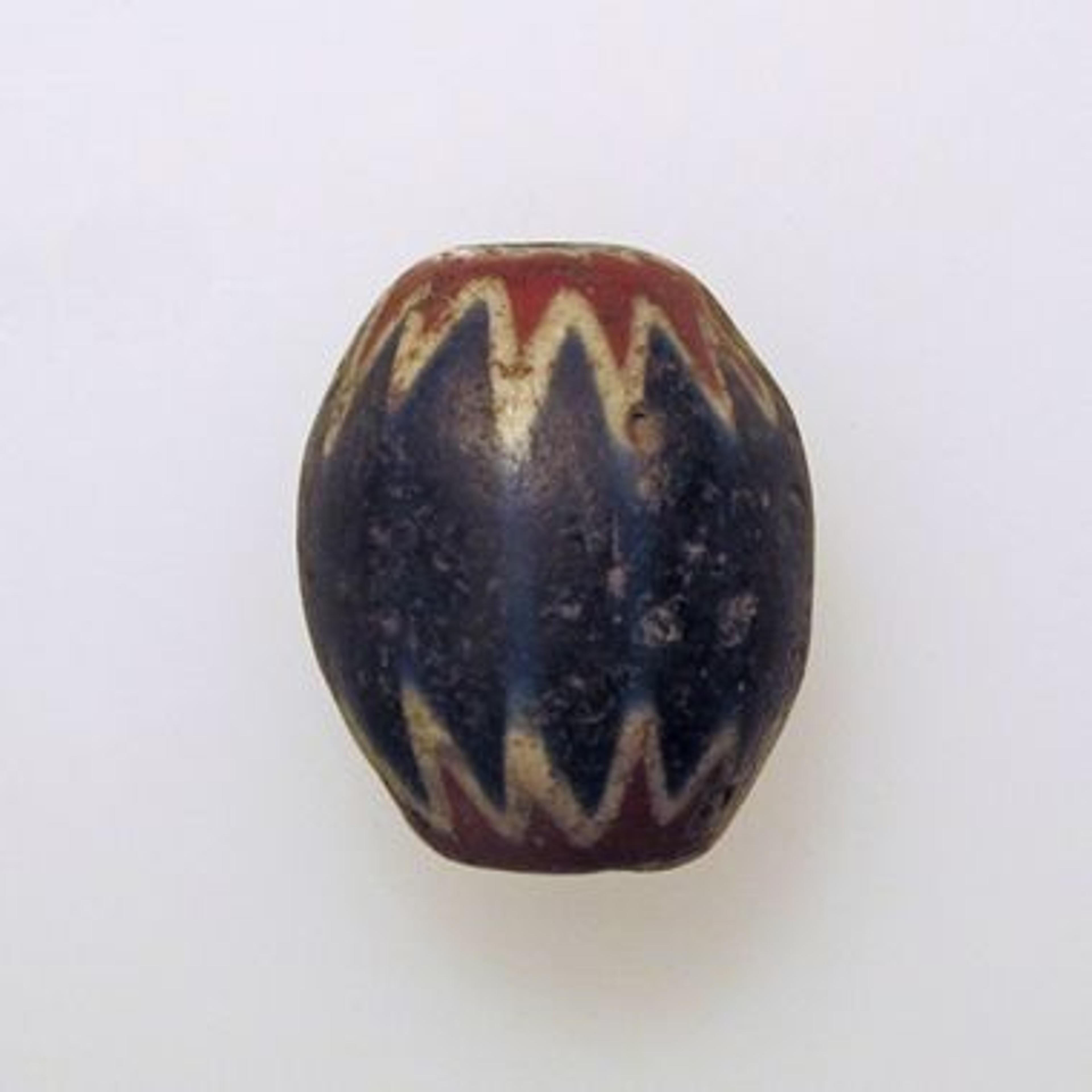 A blue, red, and gold glass bead with a chevron design