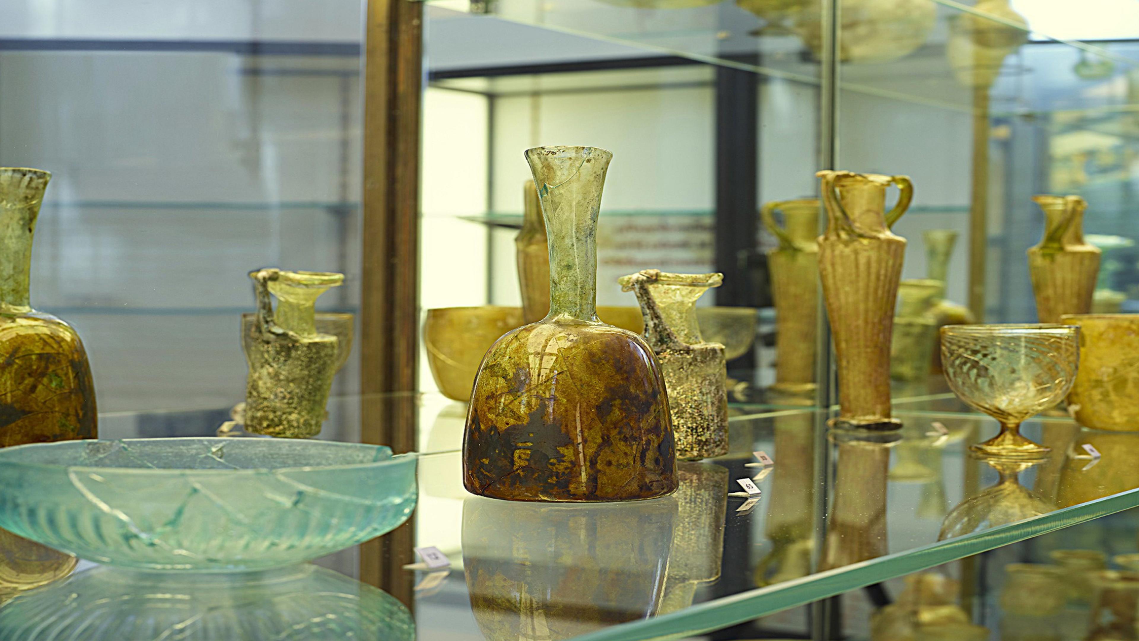 Display case with a shelf of yellow-tinted glassware.