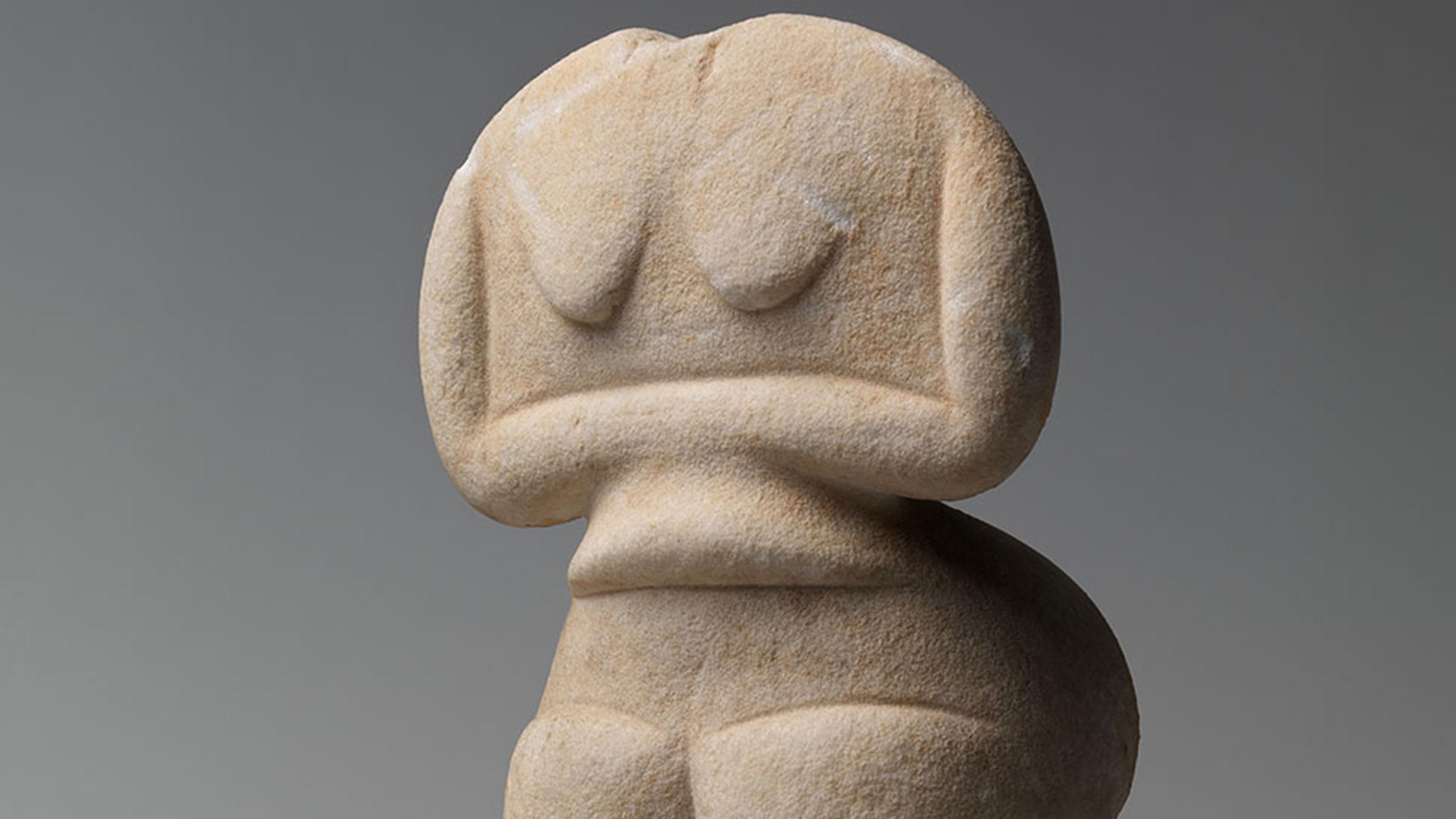 A small, smooth stone figure with no head, exaggerated thighs and minimalist features.