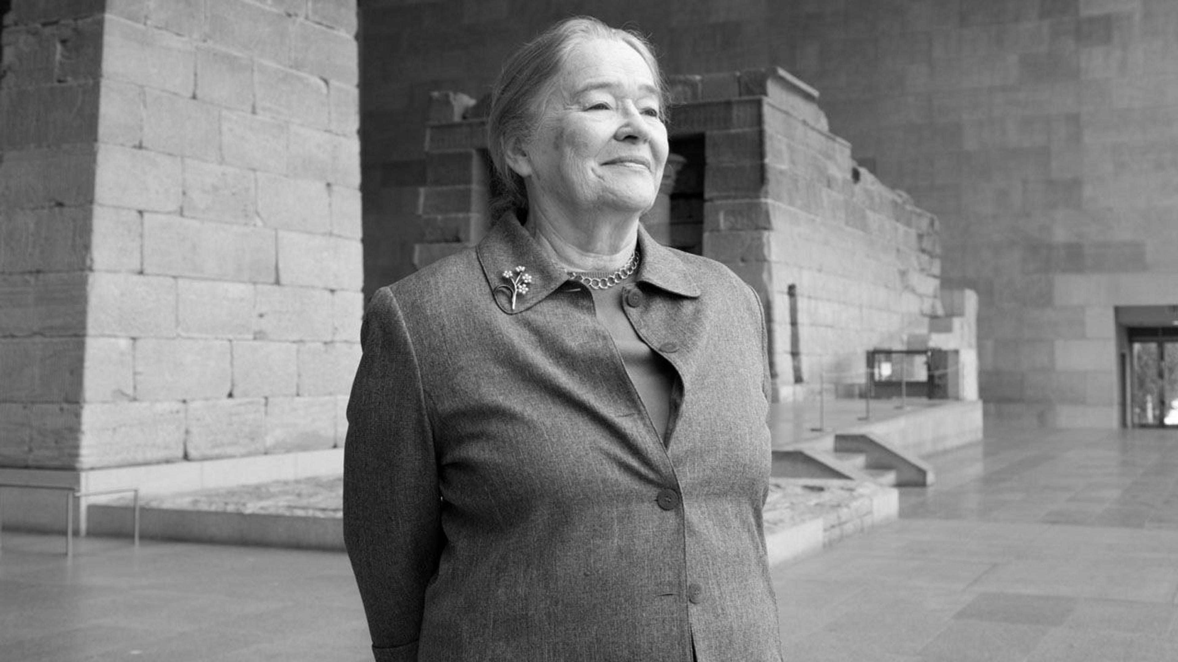 Black and white photograph of curator Dorothea Arnold standing in the Temple of Dendur at The Met