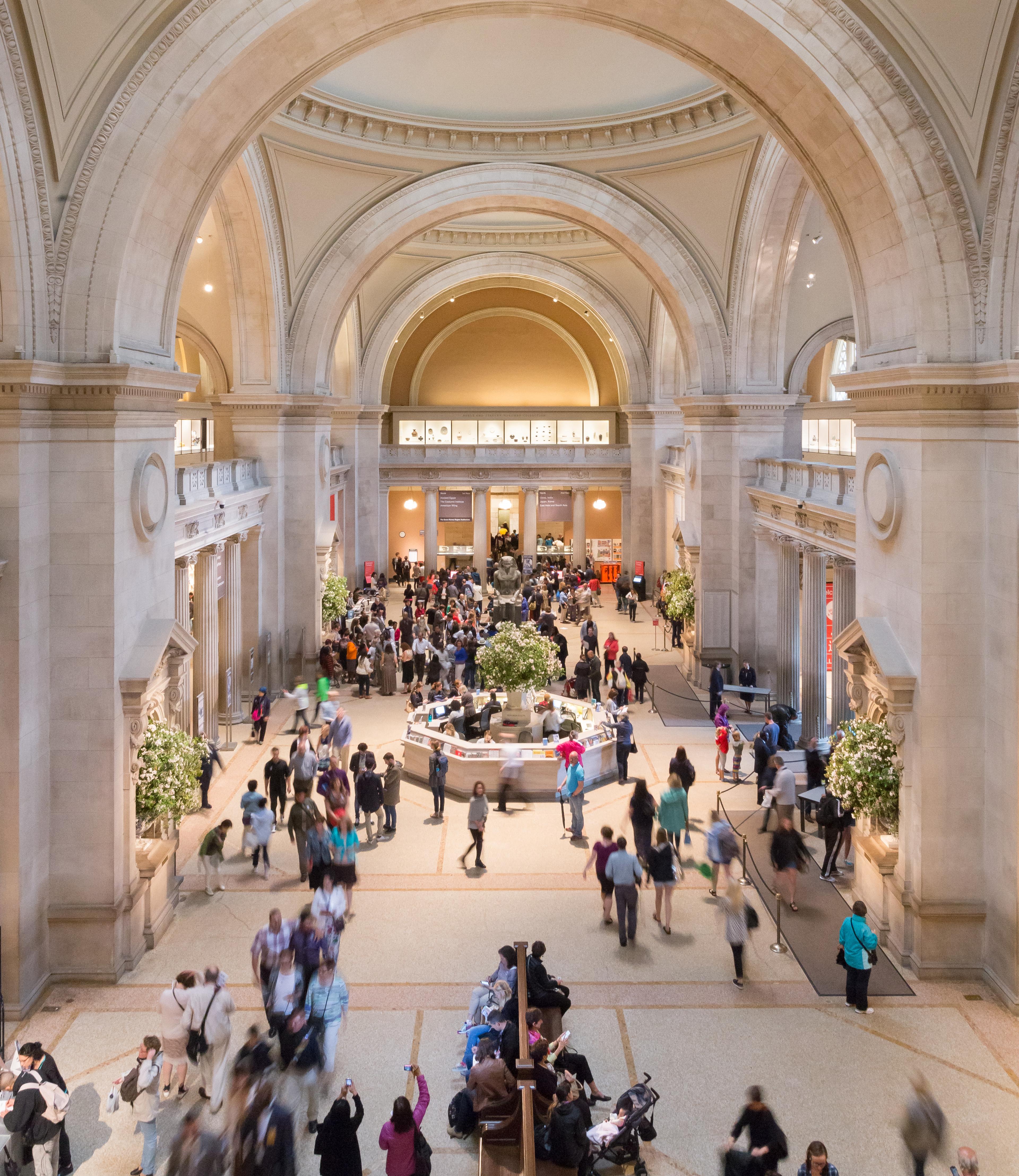 The Met's Great Hall filled with crowds captured in movement.