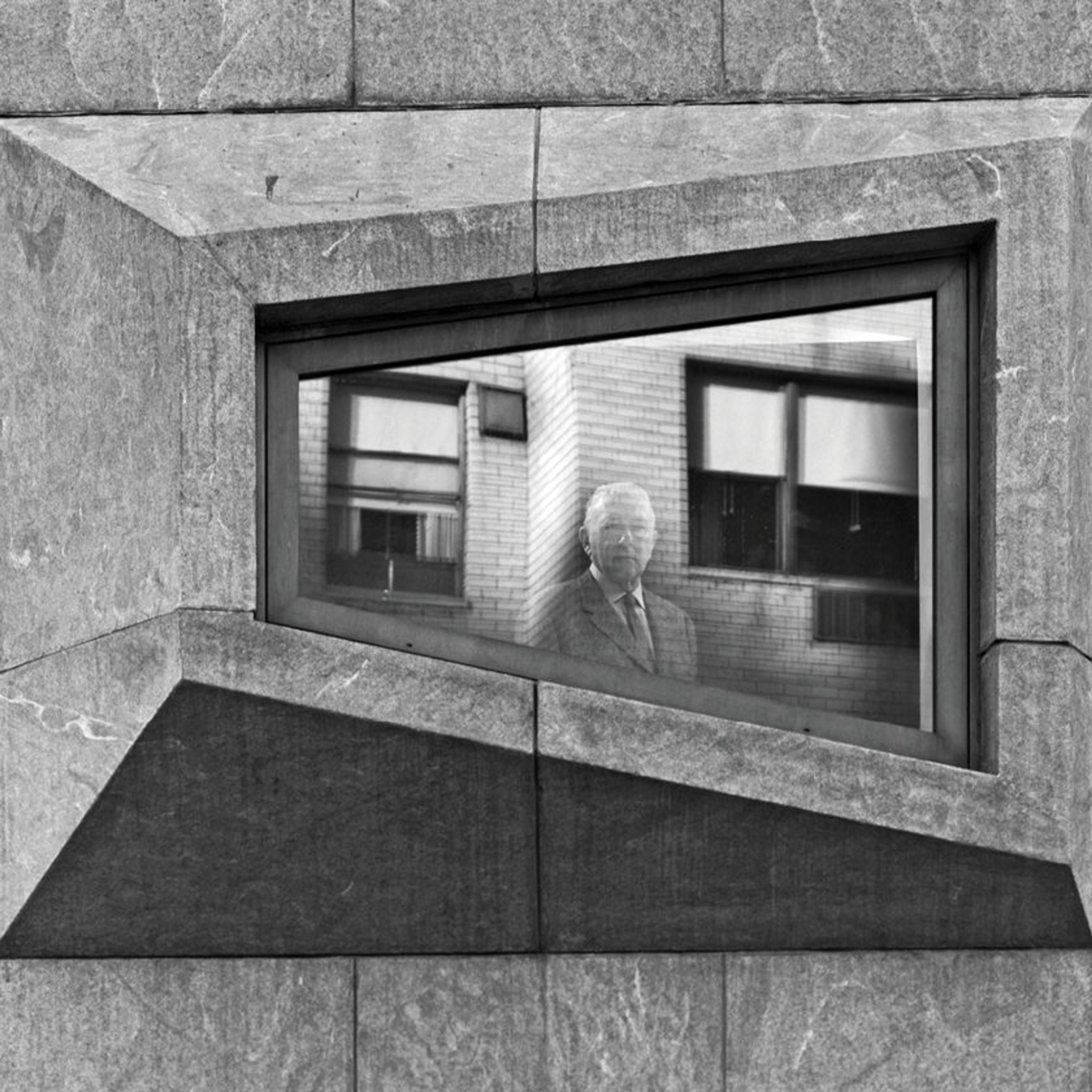 Black-and-white image of a window on Marcel Breuer's iconic building at Madison and 75th Street, with the architect himself visible in the window