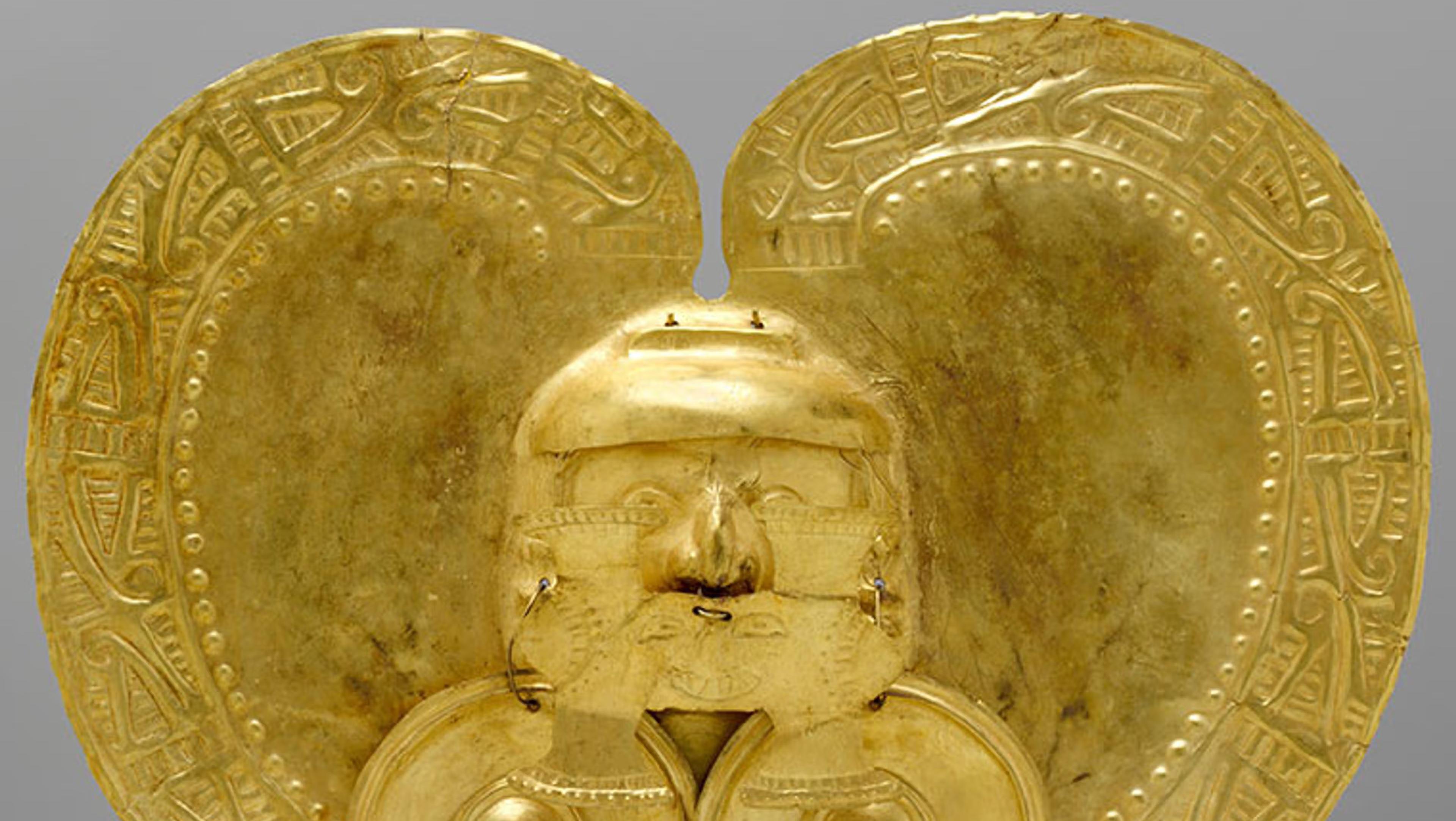 A  heart-shaped gold pendant with a relief of a face in the center and two golden circles hanging off of the face's ears.