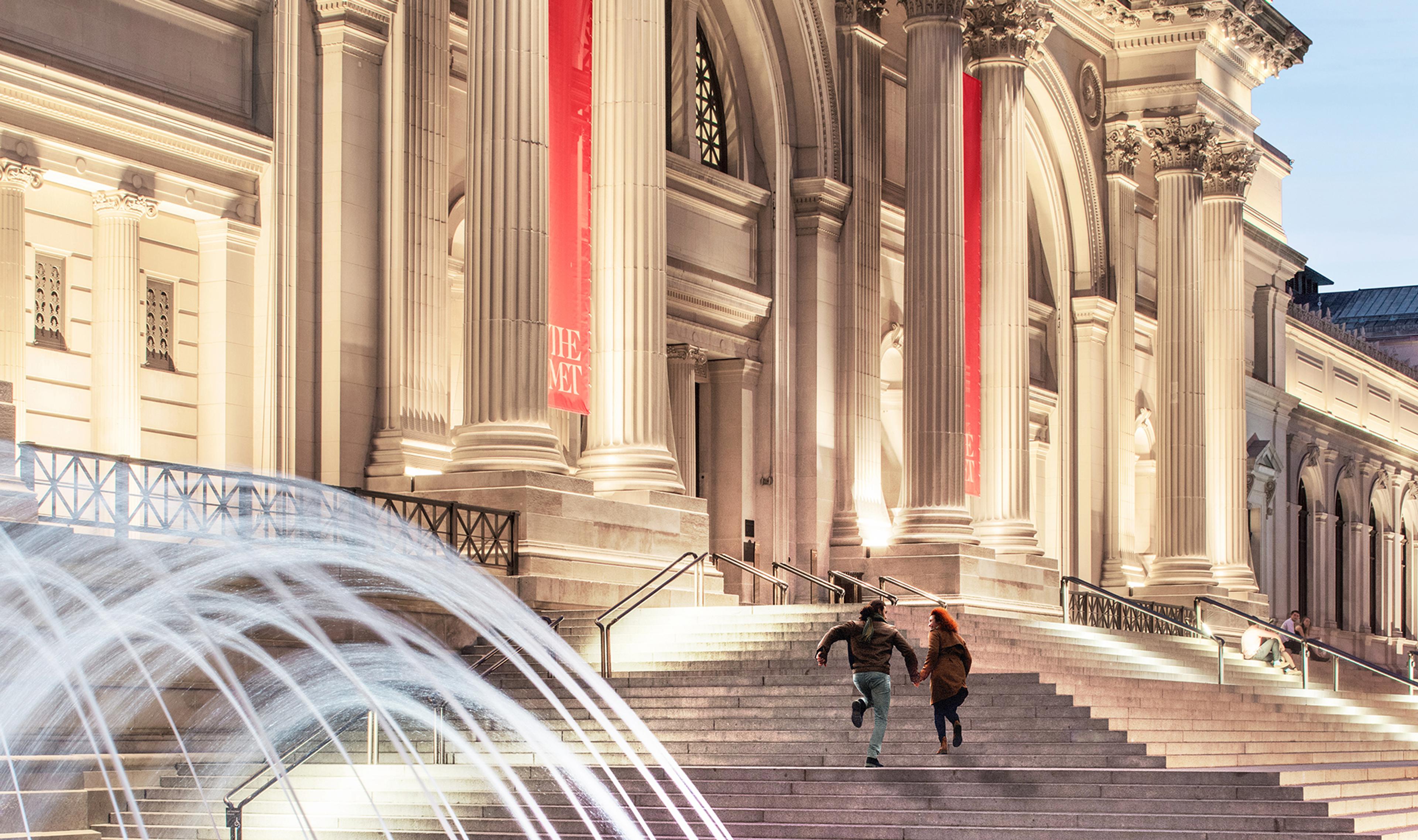 A couple runs up The Met steps at dusk.