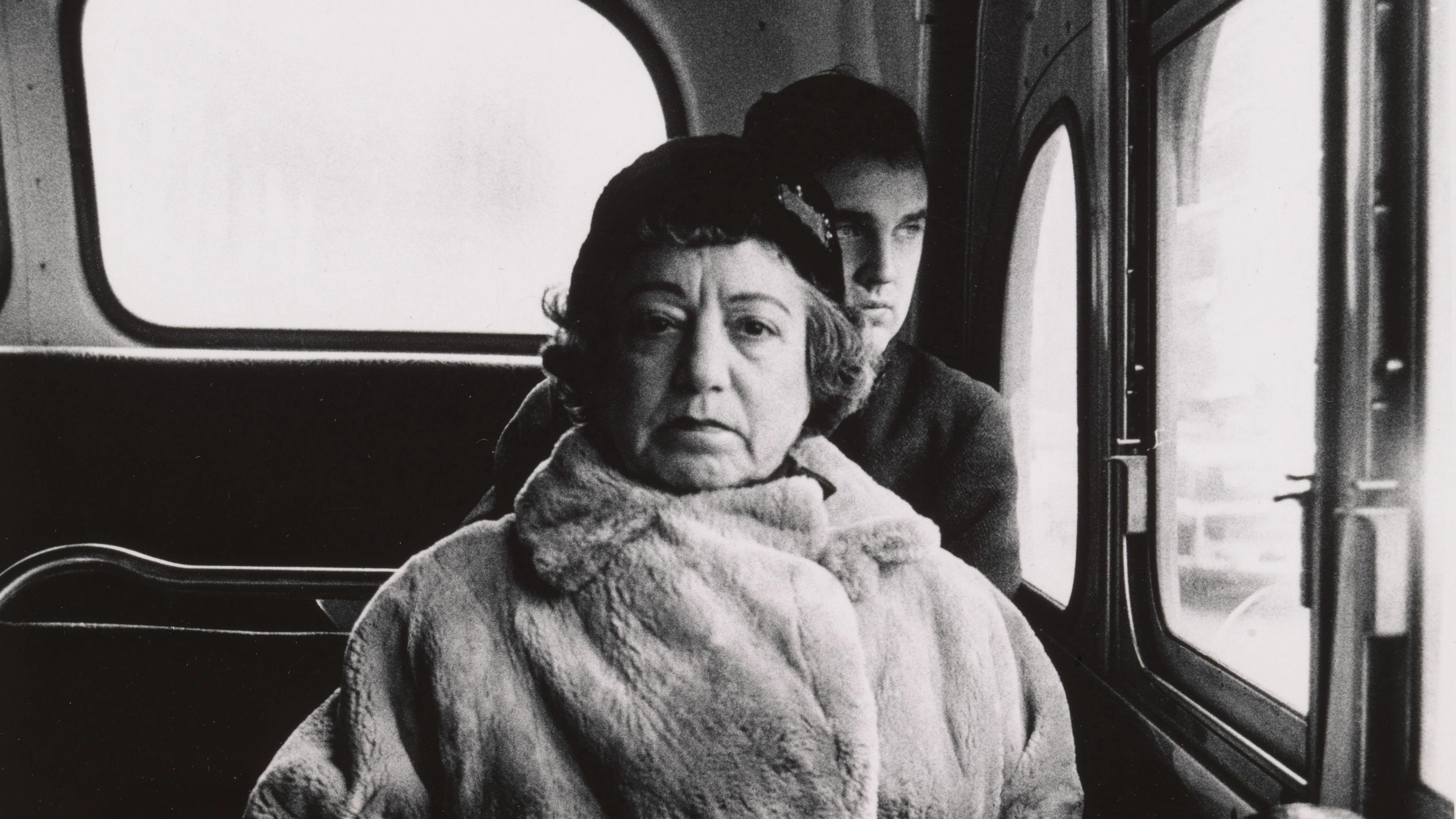Black-and-white photograph of a woman on a bus.