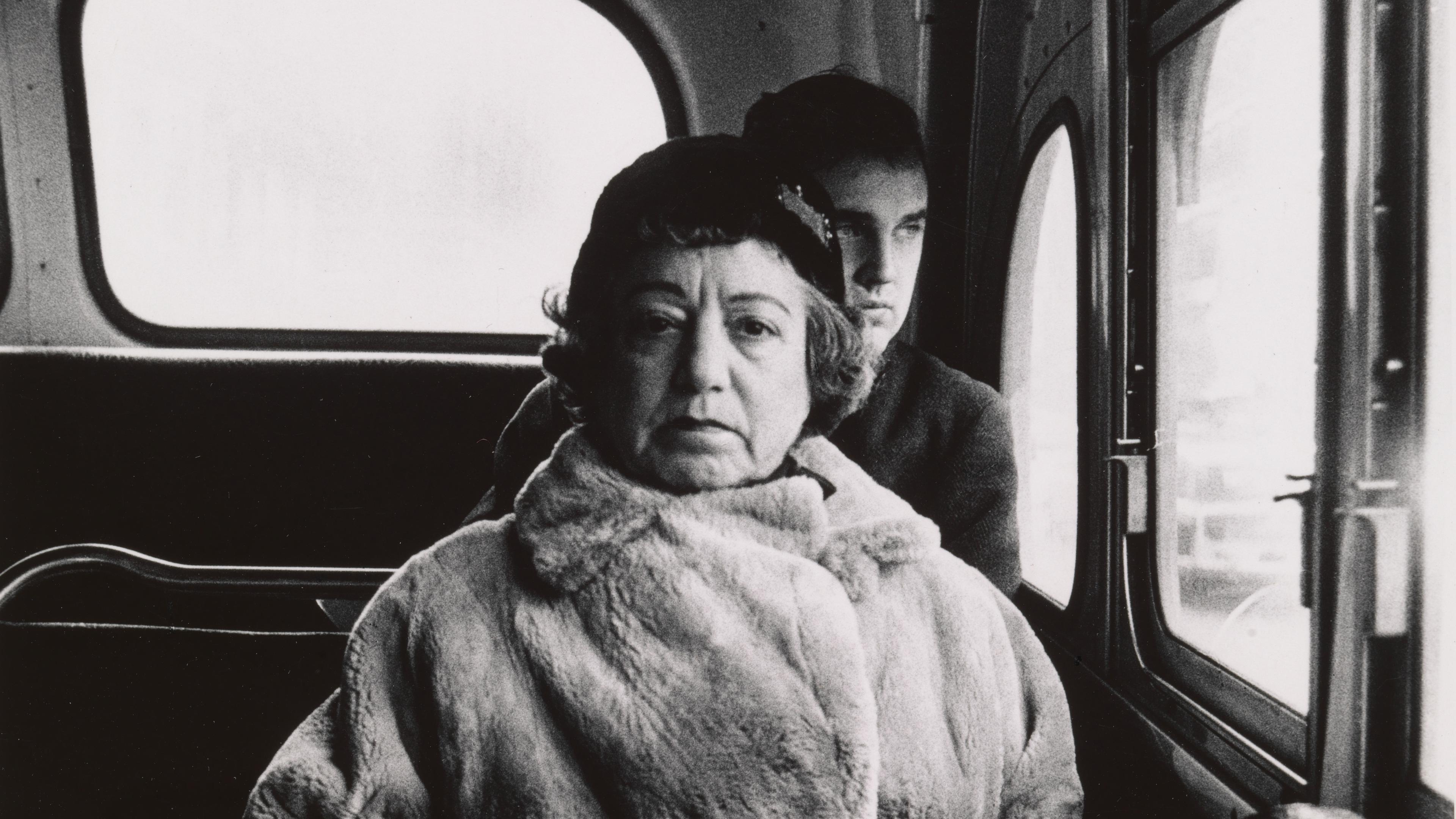 Black-and-white photograph of a woman on a bus.