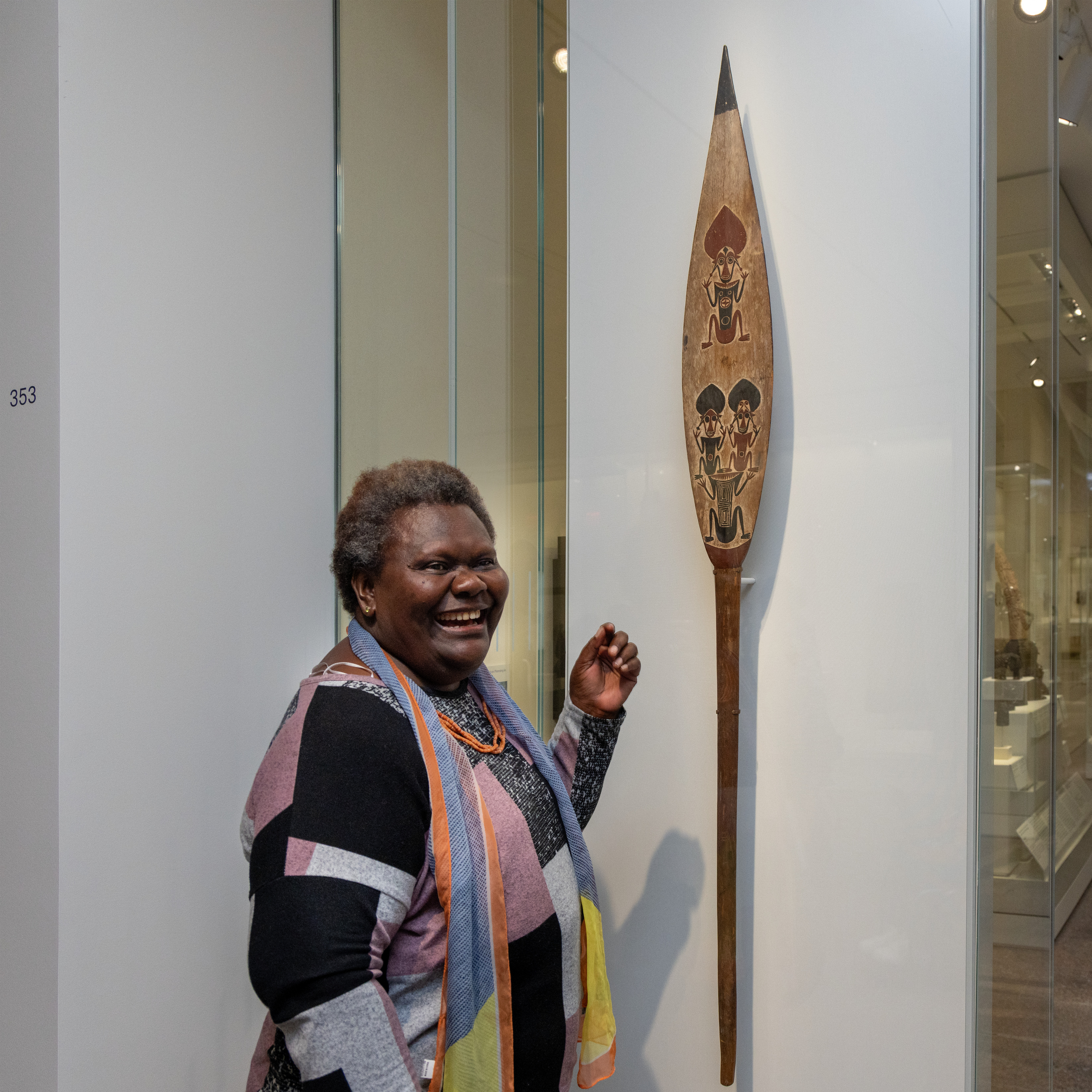 Sana Balai standing in front of a ceremonial paddle in the Oceania galleries at The Met.