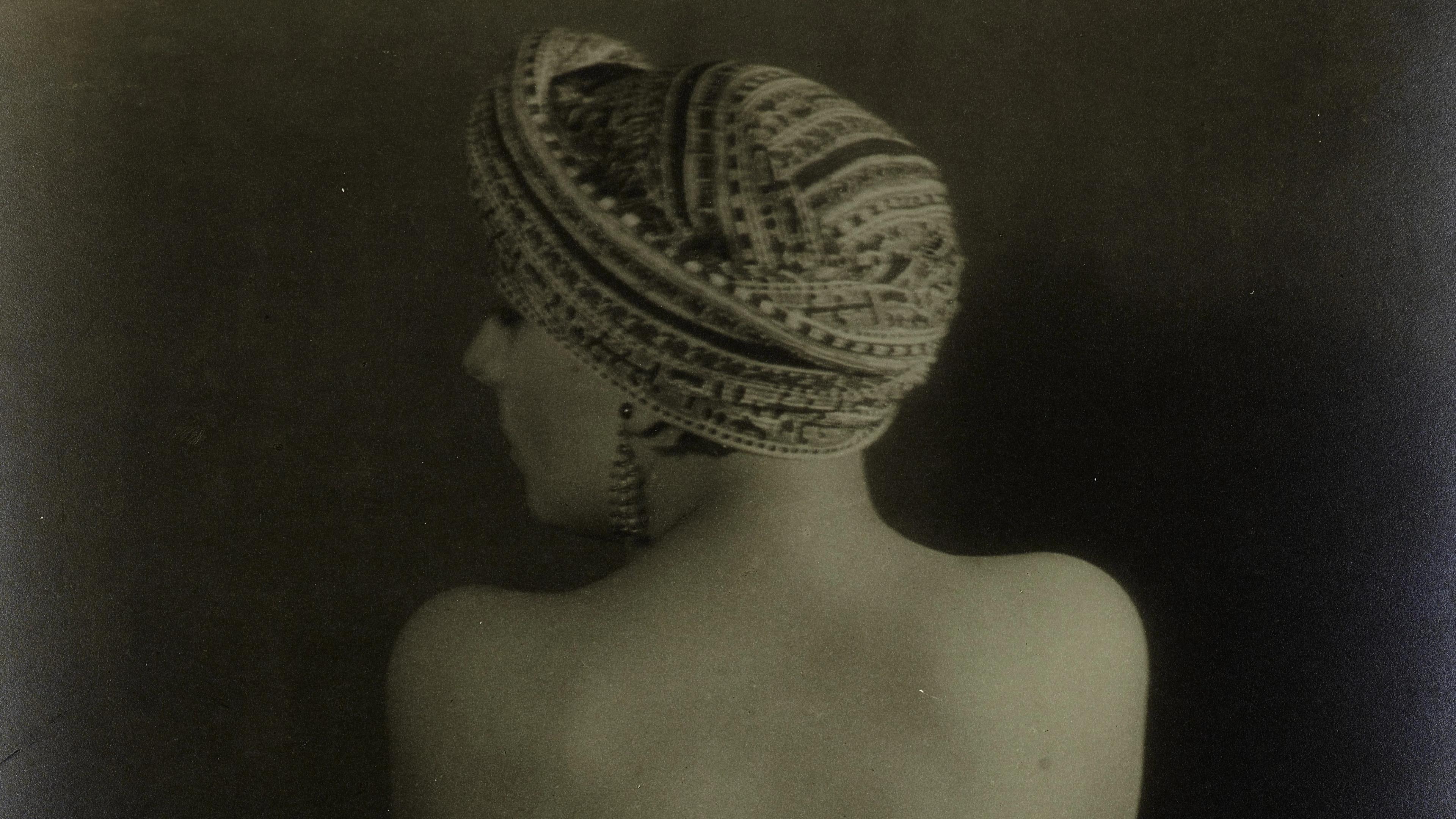 A woman in a patterned hat and earring turned away from the camera