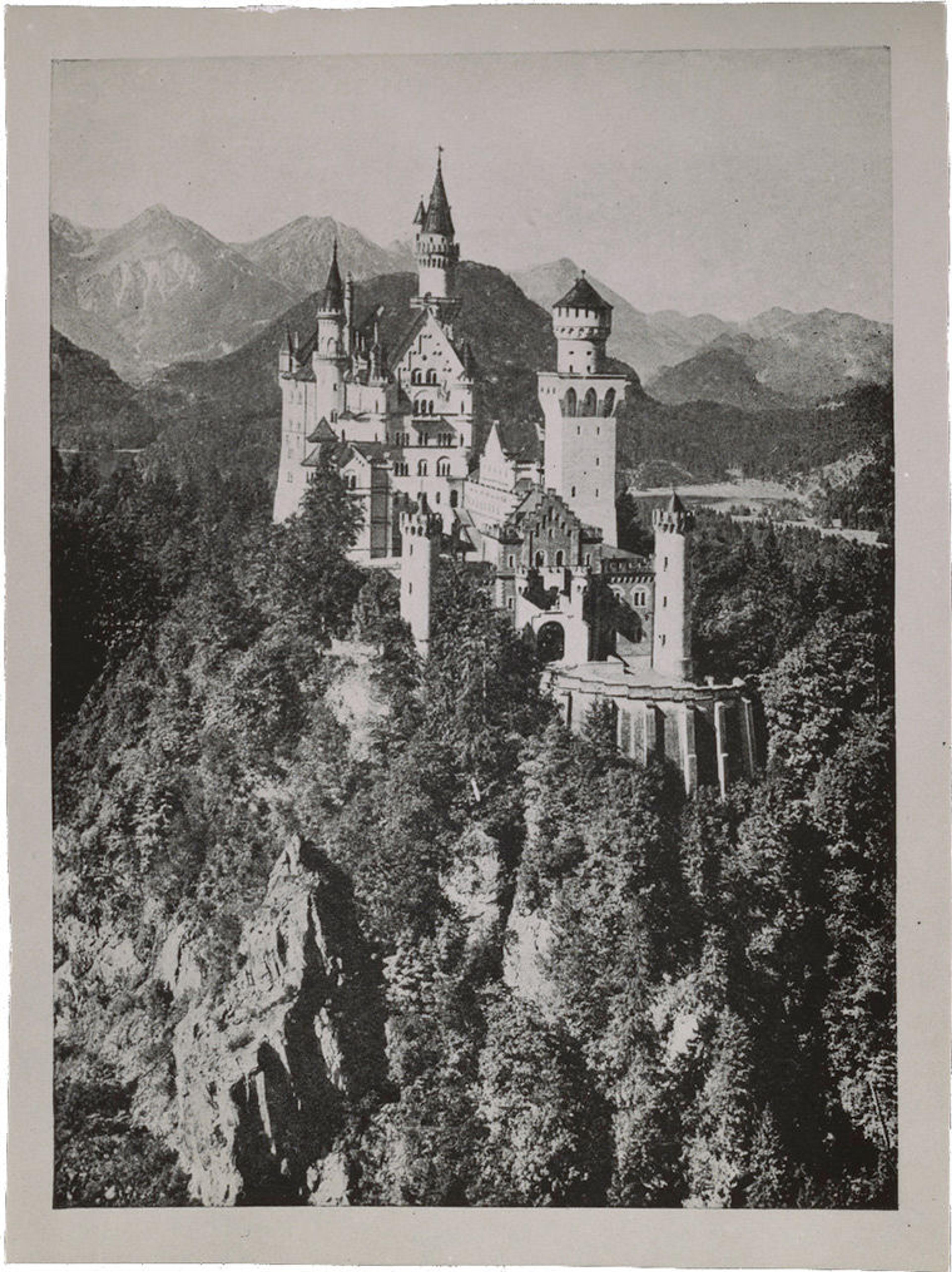 Black-and-white photograph of a fairy-tale style castle perched on a rocky mountain