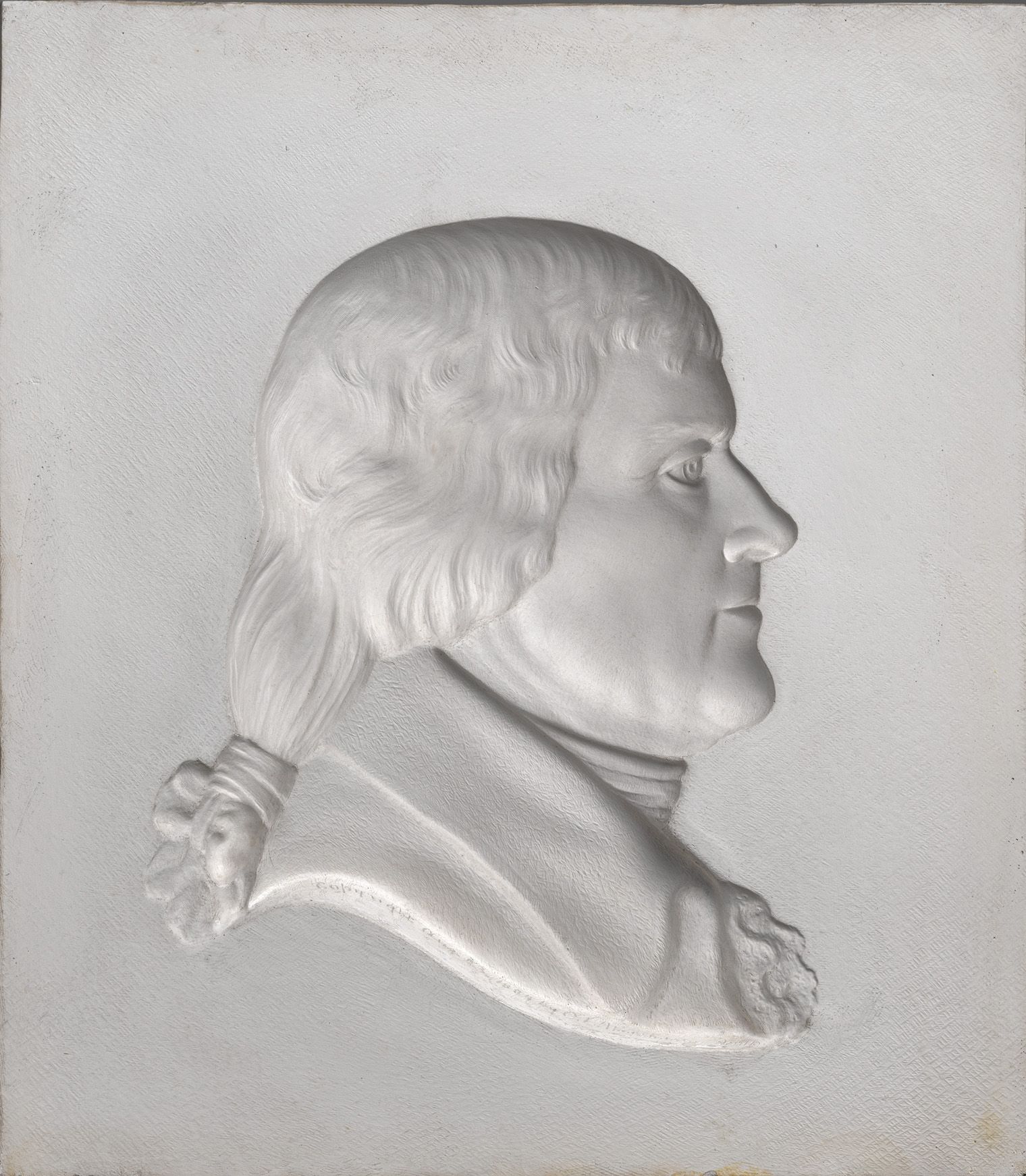White plaster relief portrait of a powdered-haired man in profile, wearing a tied ponytail and formal coat