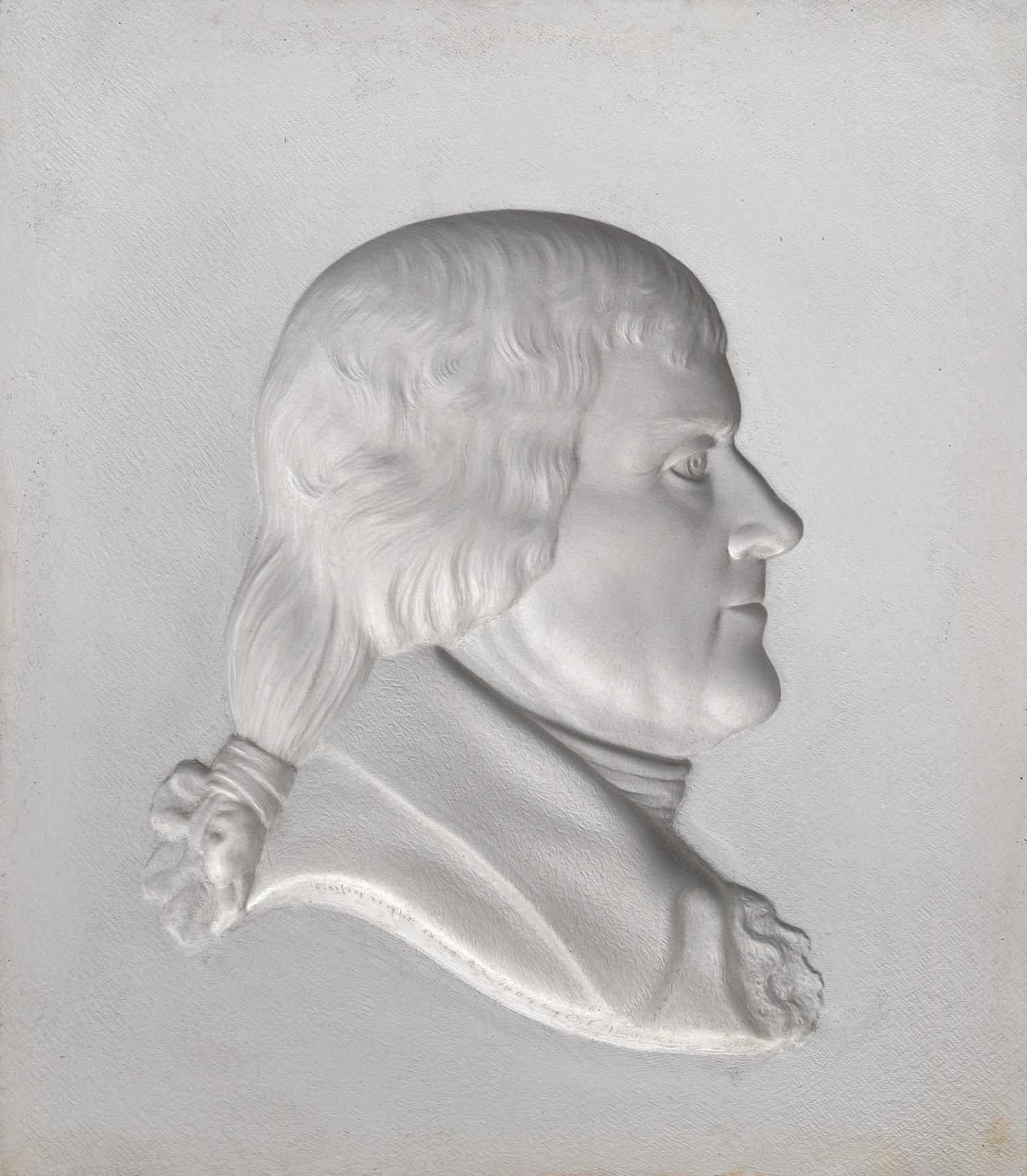 White plaster relief portrait of a powdered-haired man in profile, wearing a tied ponytail and formal coat