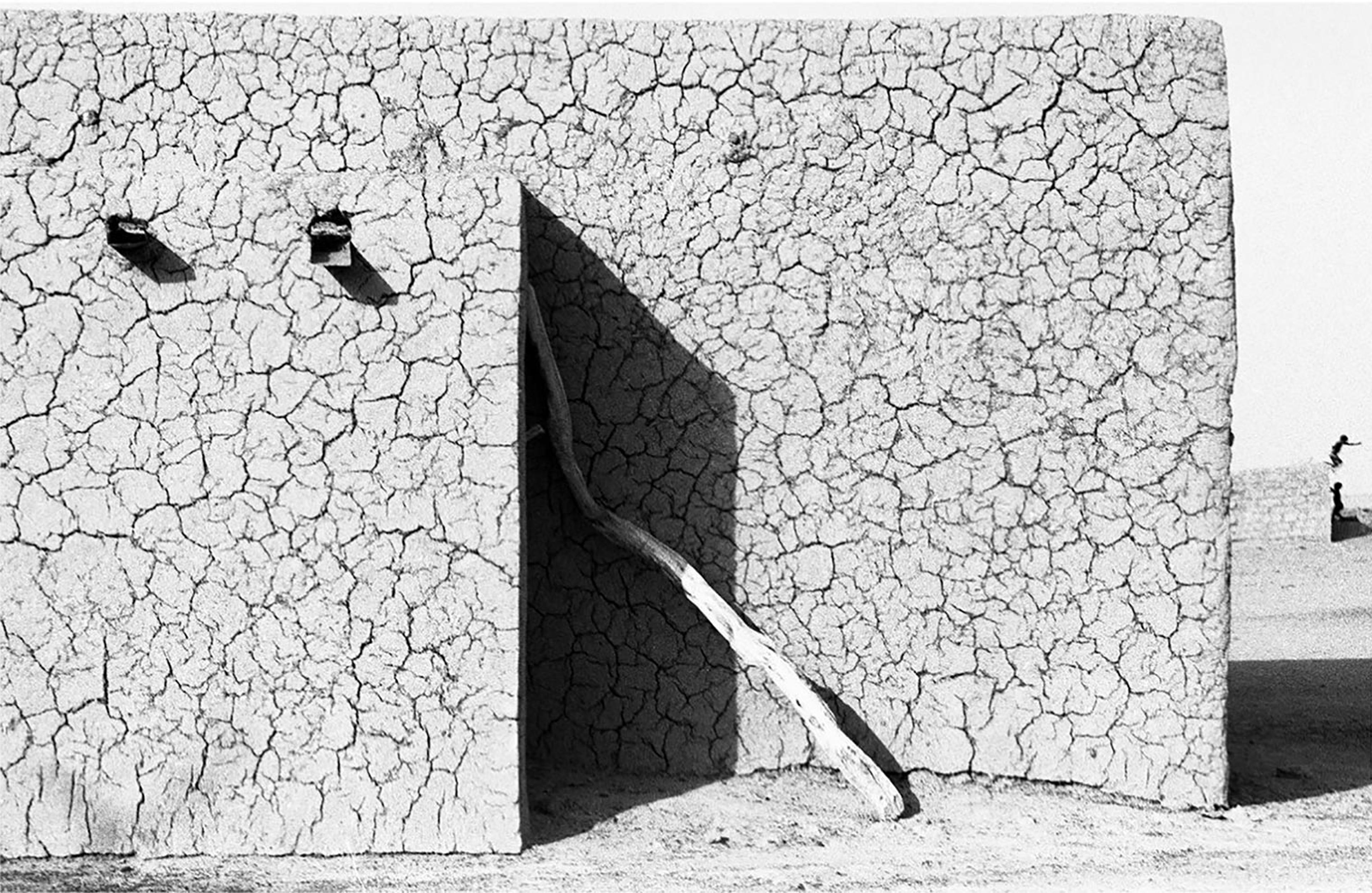 A black and white photo of a simple mud building