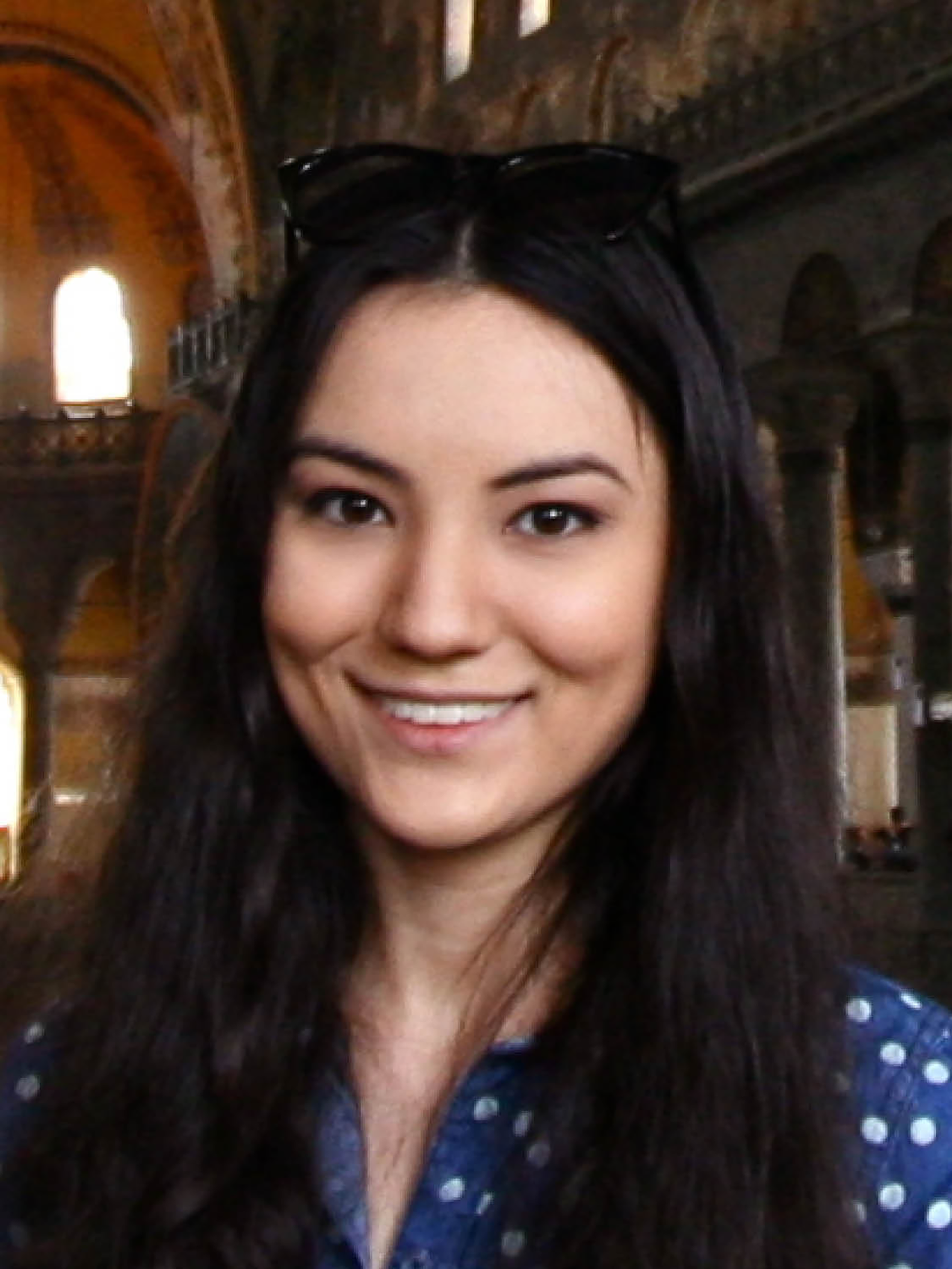 A woman with long hair stands in a domed, antique building