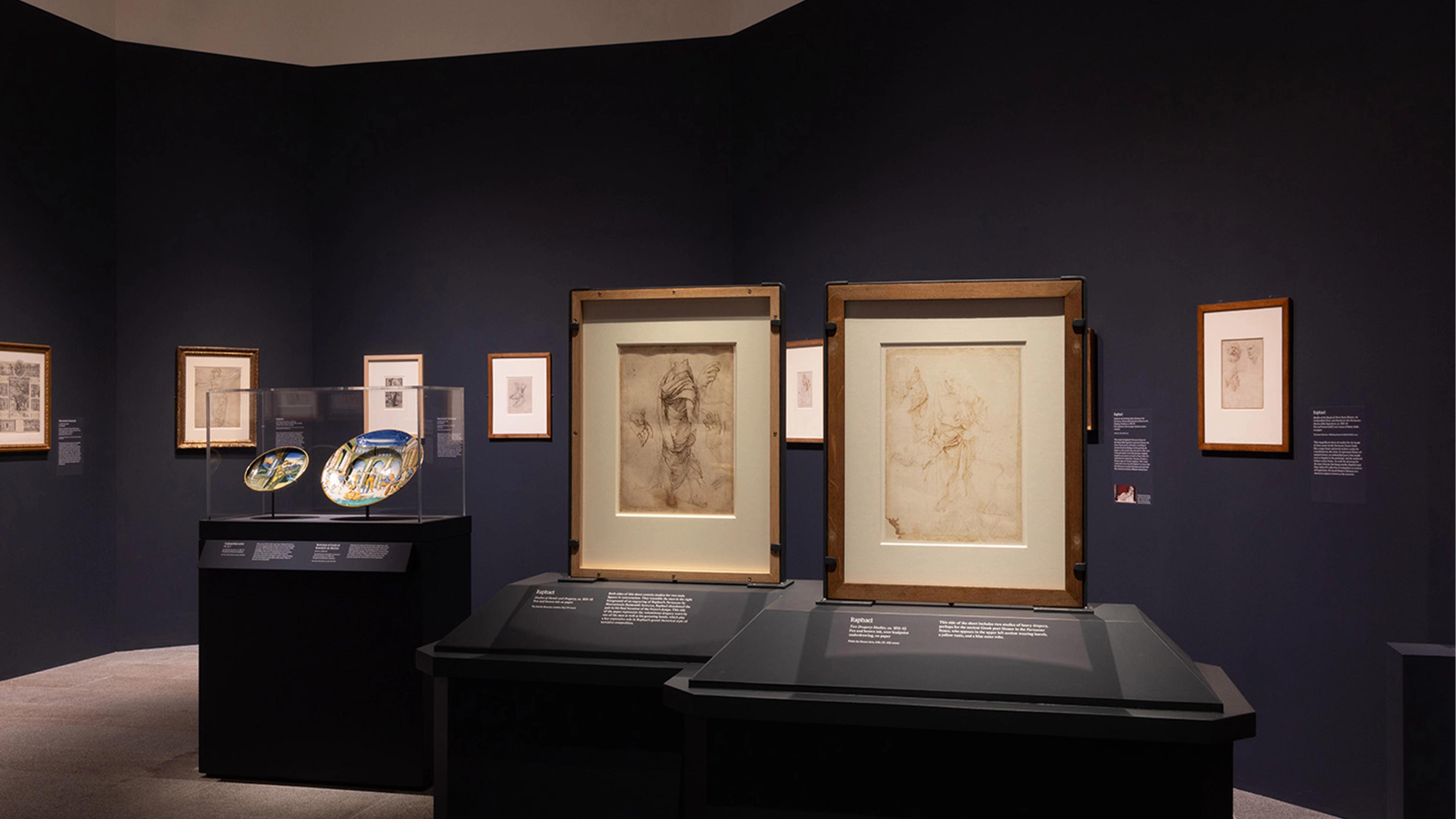 The gallery room features framed sketches on dark walls, illuminated under soft lighting.