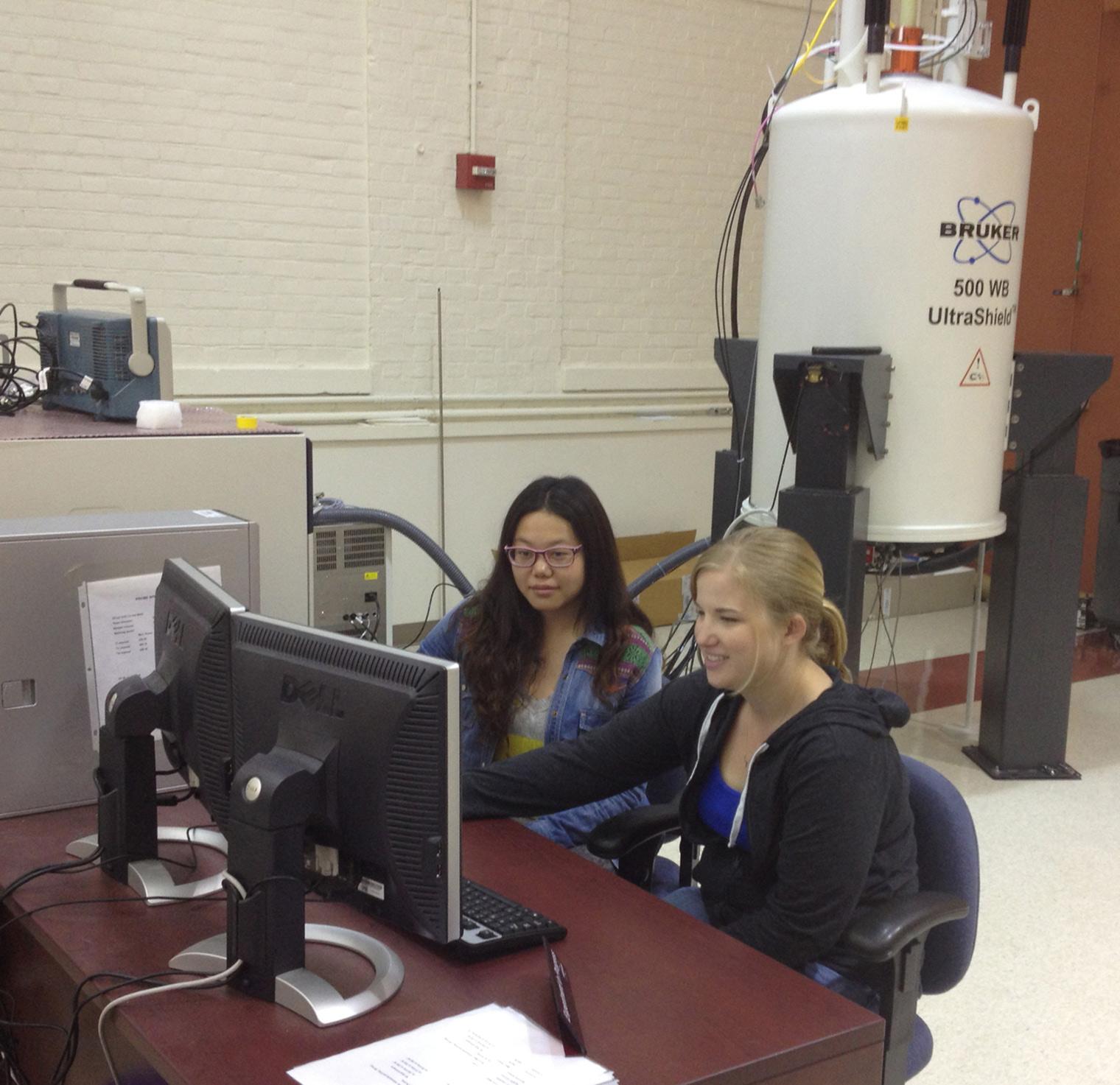 Two students seated in front of a computer.