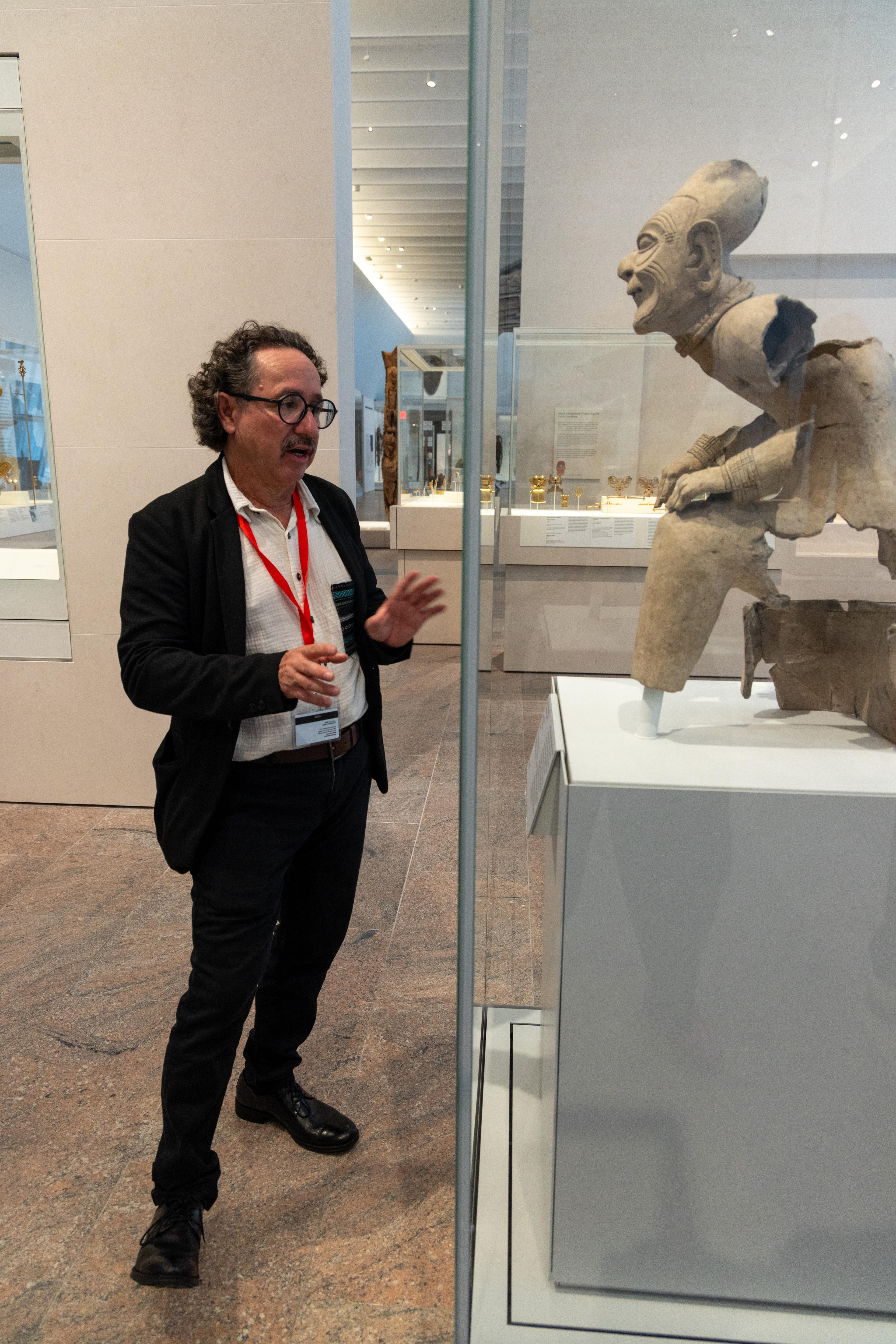 Florencio Delgado Espinoza speaks in front of the seated elder statue in the Arts of the Ancient Americas galleries.