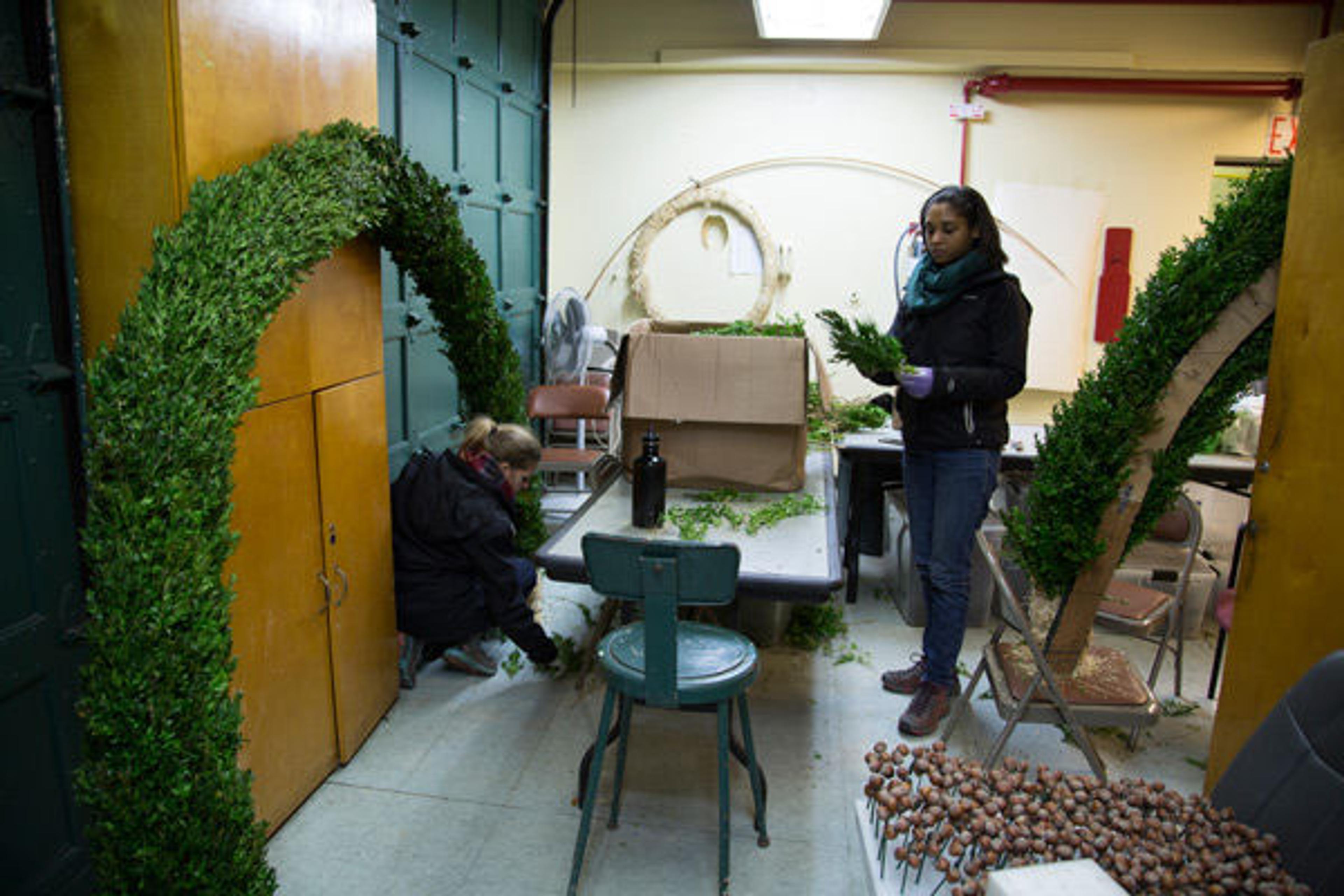 Carly and Yvette cover the wood and straw arch forms with boxwood