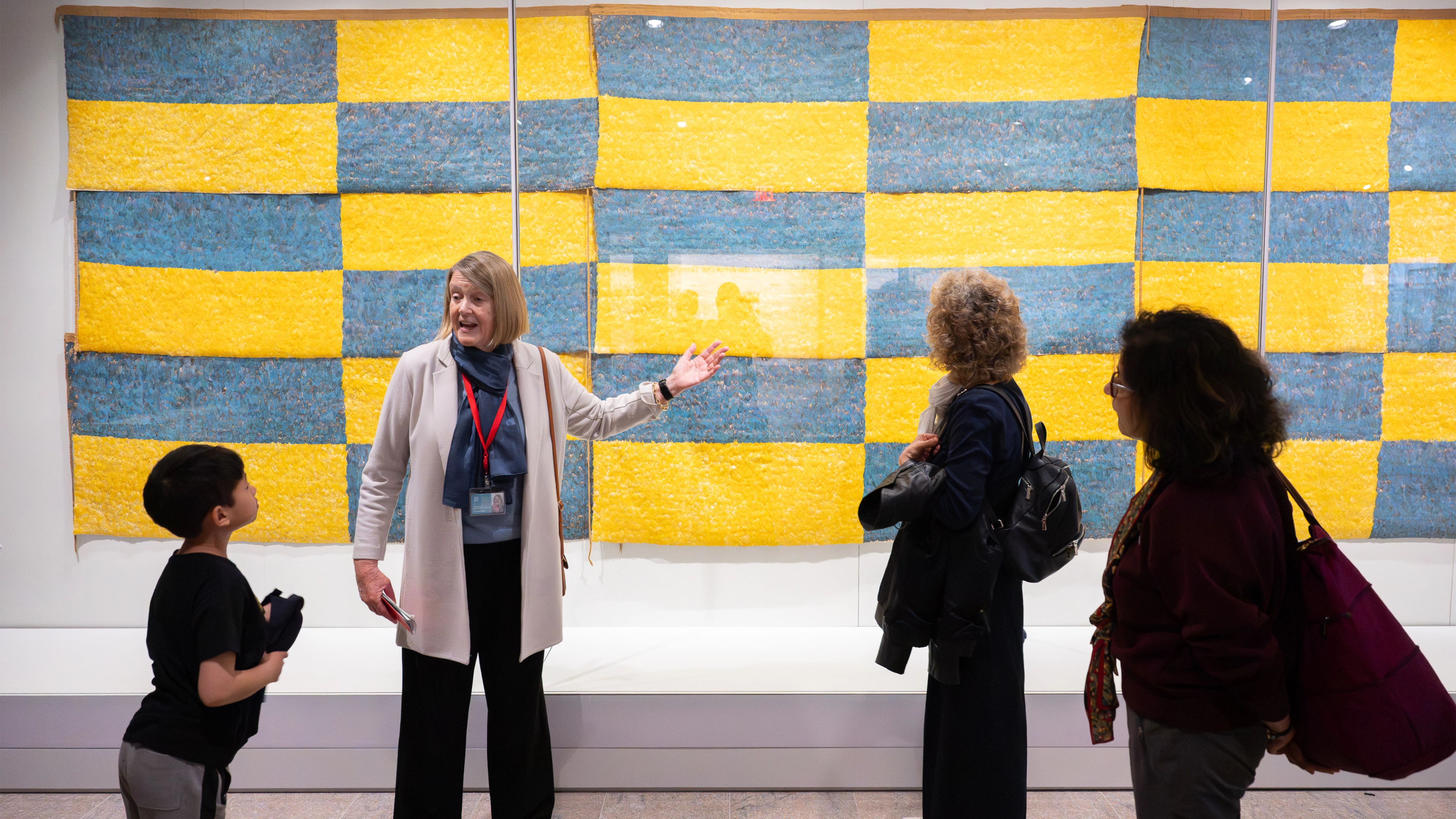 A tour guide points at an artwork with a group surrounding them. 