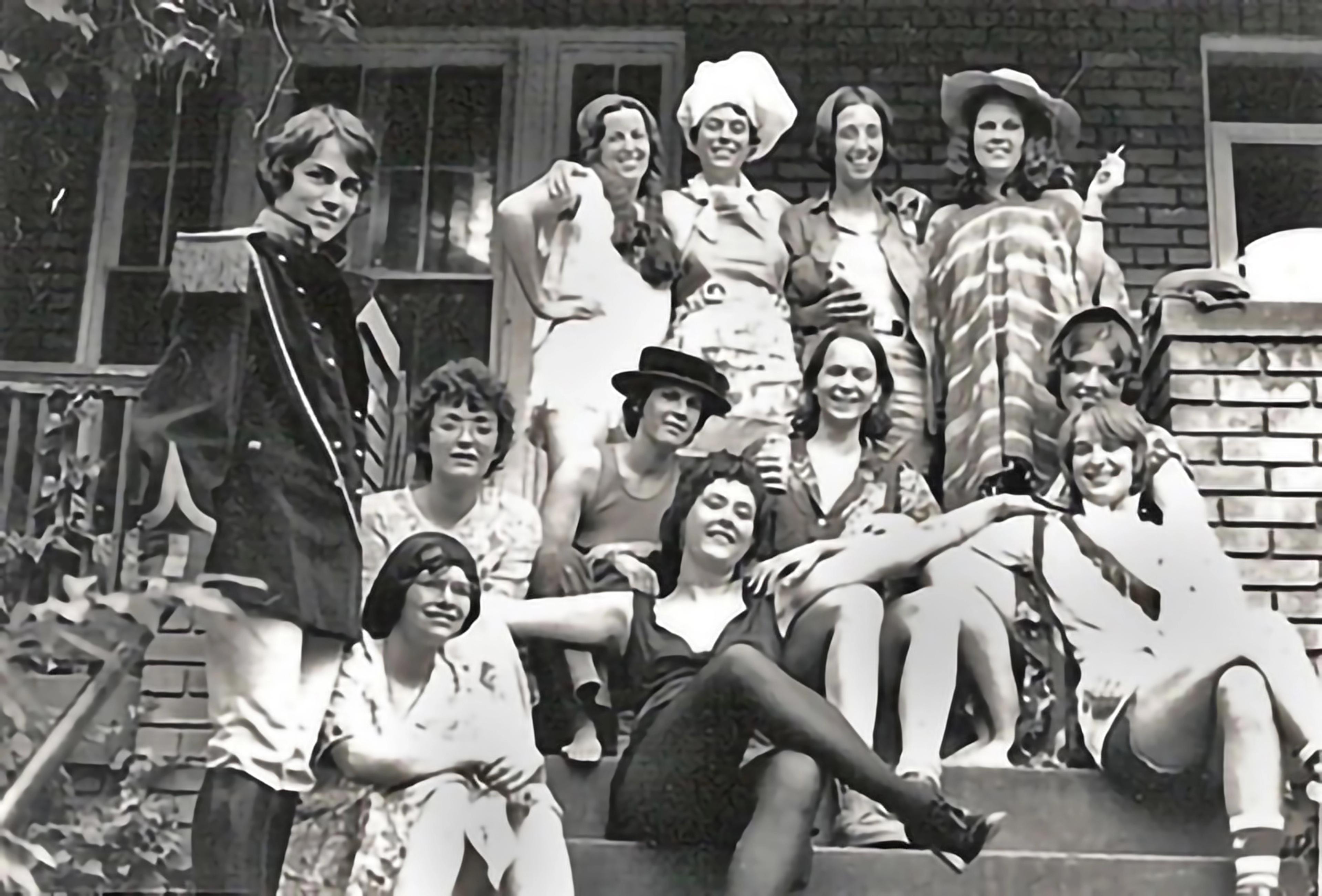 Black-and-white photograph of women in costume, posing outside on a stoop.