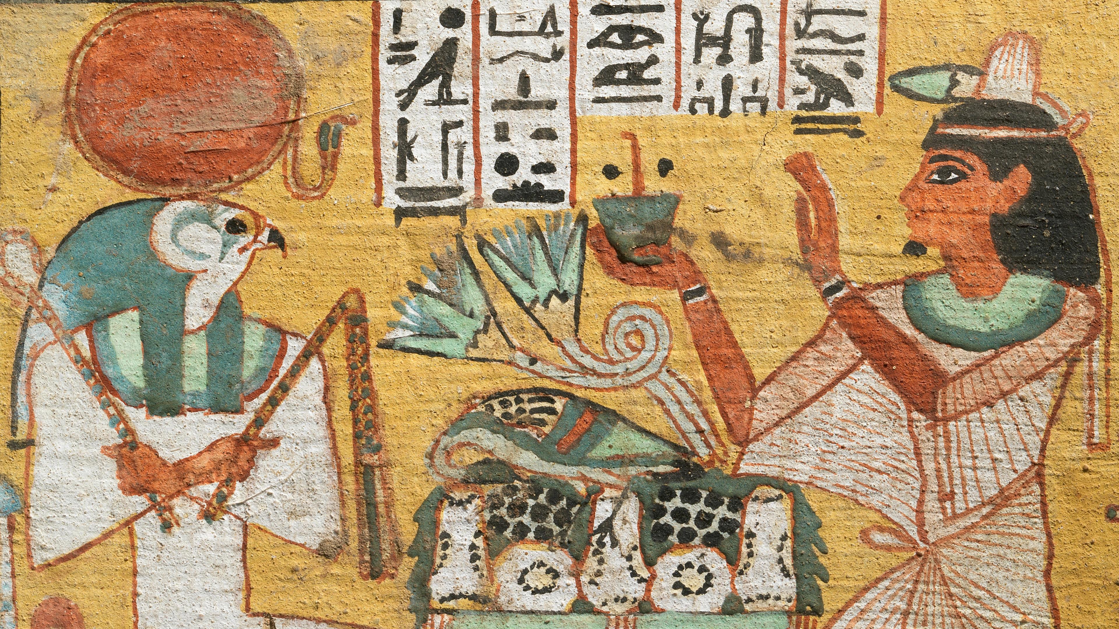 An ancient Egyptian painting of a falcon-headed god being approached by a man holding a vessel