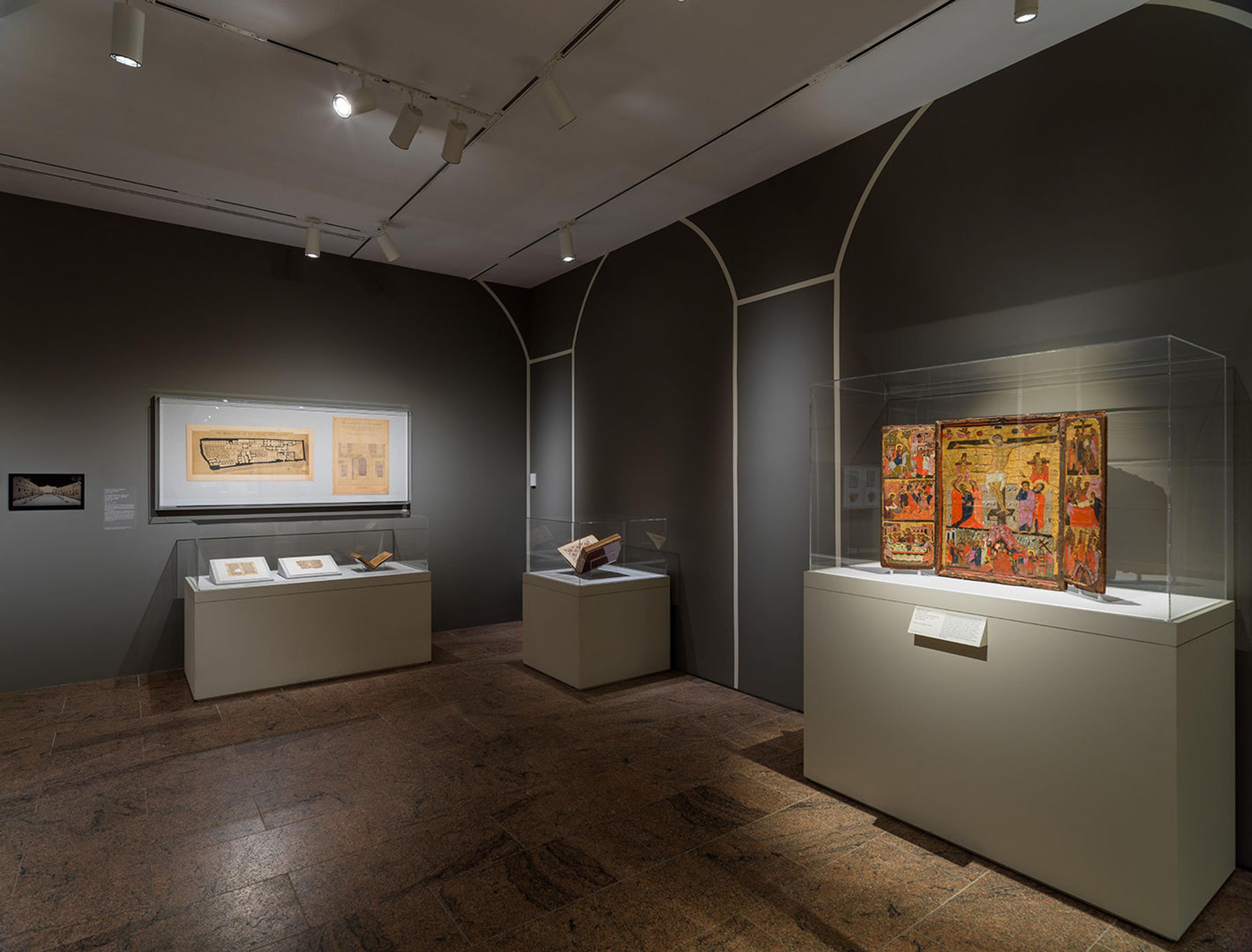 Gallery view from the Africa & Byzantium exhibition. The room is dark, with three glass exhibit cases.