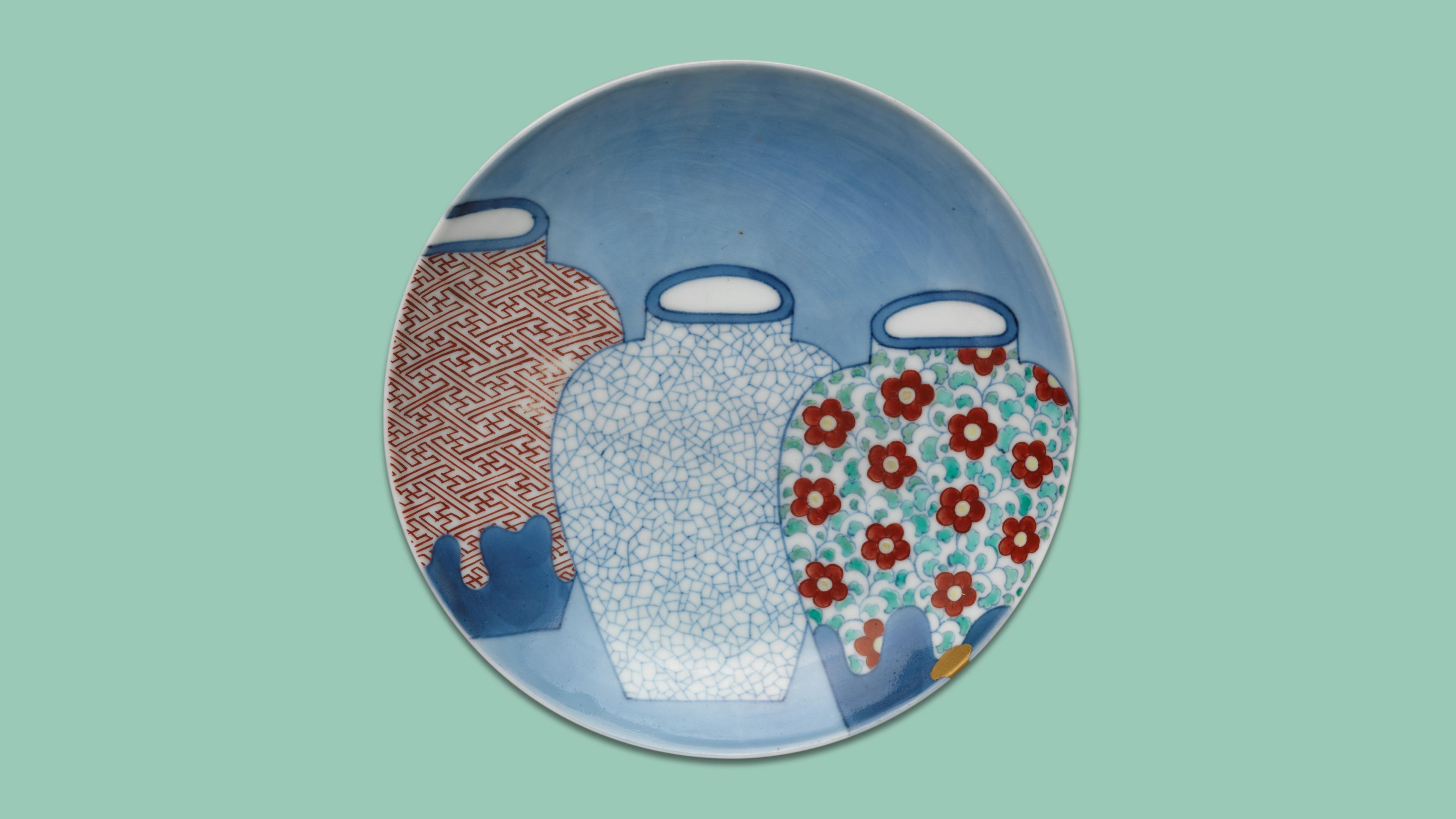 Ceramic plate with three overlapping vases. Left vase has red geometric patterns, middle is white with blue cracks, and right has red flowers on light blue.