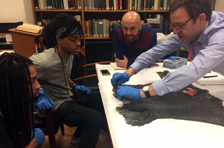 Two teenagers and two Museum staff look at a piece of armor in The Met collection in a study area