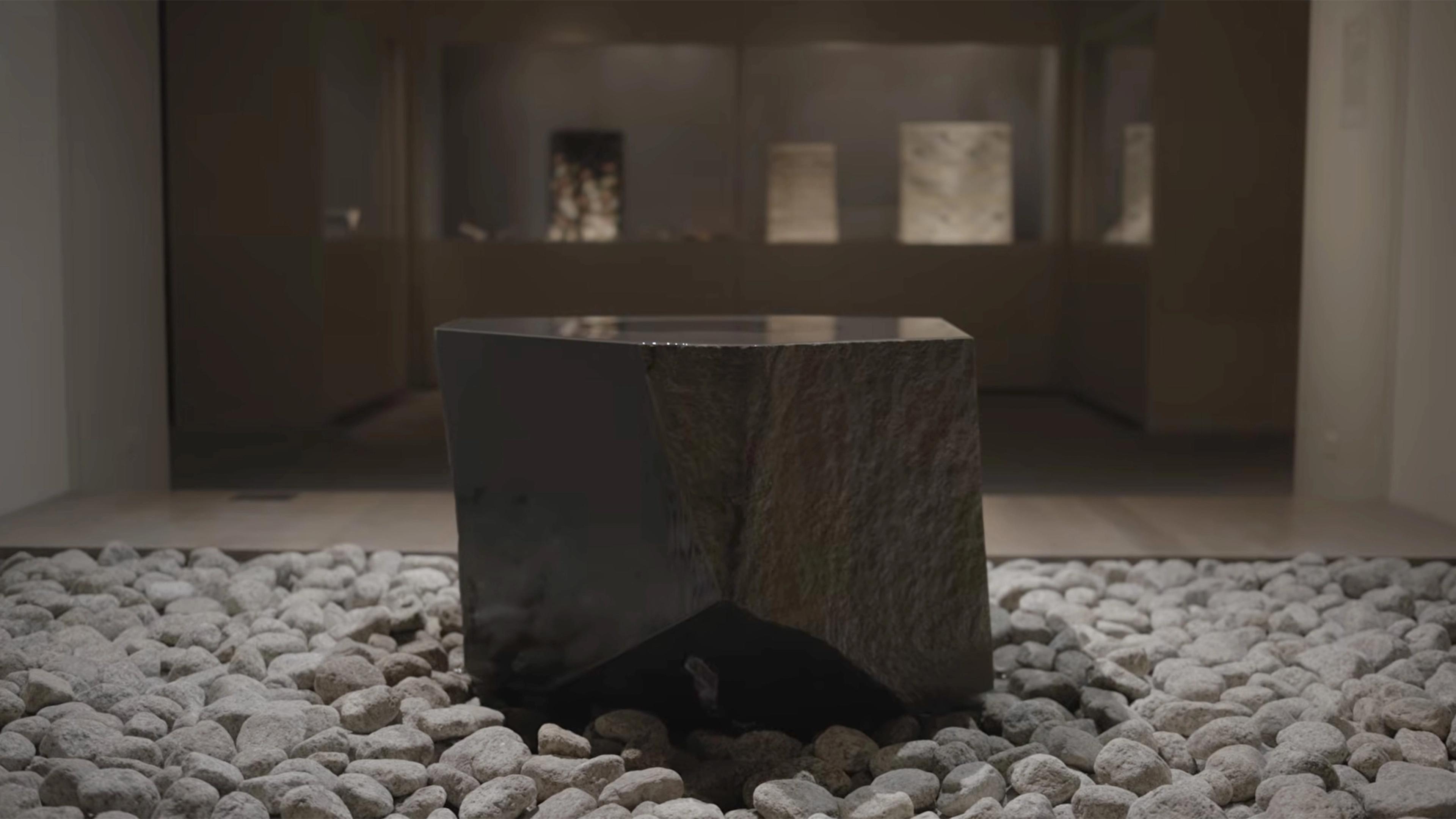 Smooth, angular stone lightly glistening with water, placed in a bed of light gray rocks.
